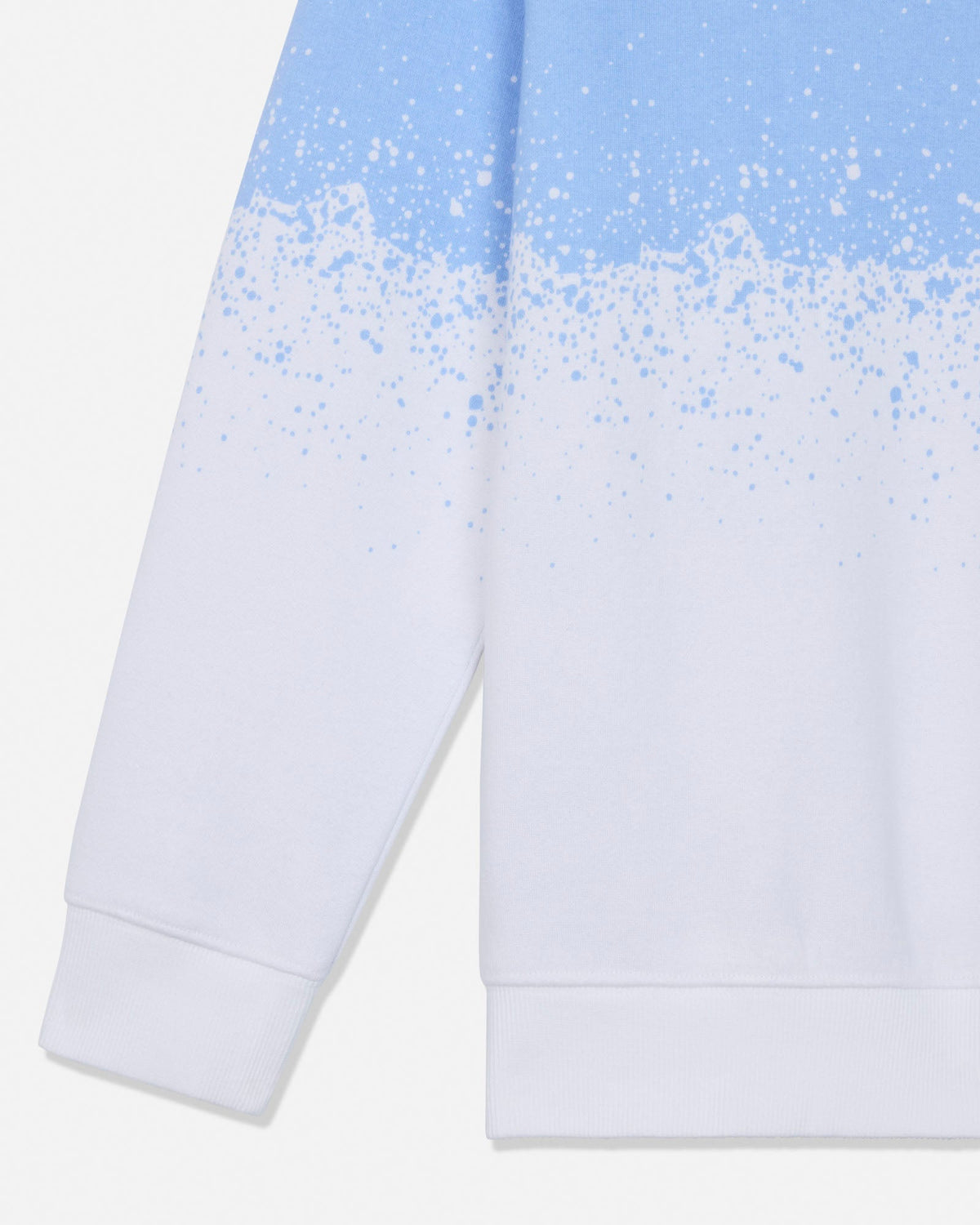 Close-up of a white sweatshirt with a light blue gradient and white paint splatter pattern across the upper chest and sleeve, on a white background.