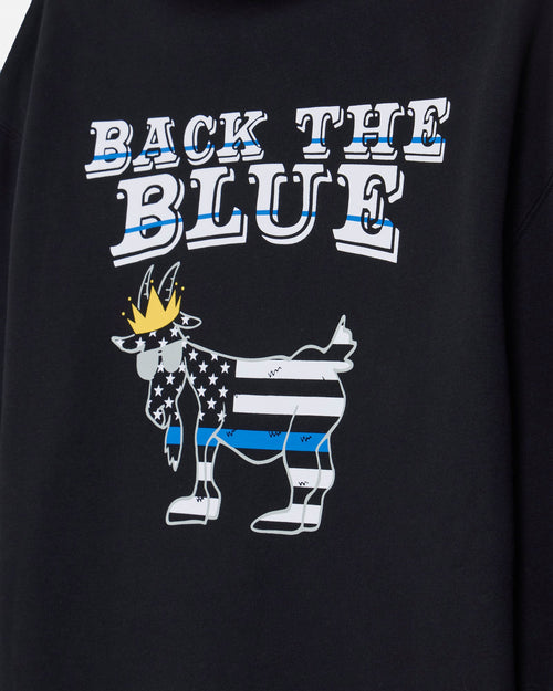 Close-up of a black sweatshirt featuring a graphic print that reads 'BACK THE BLUE' above a stylized goat filled with a U.S.