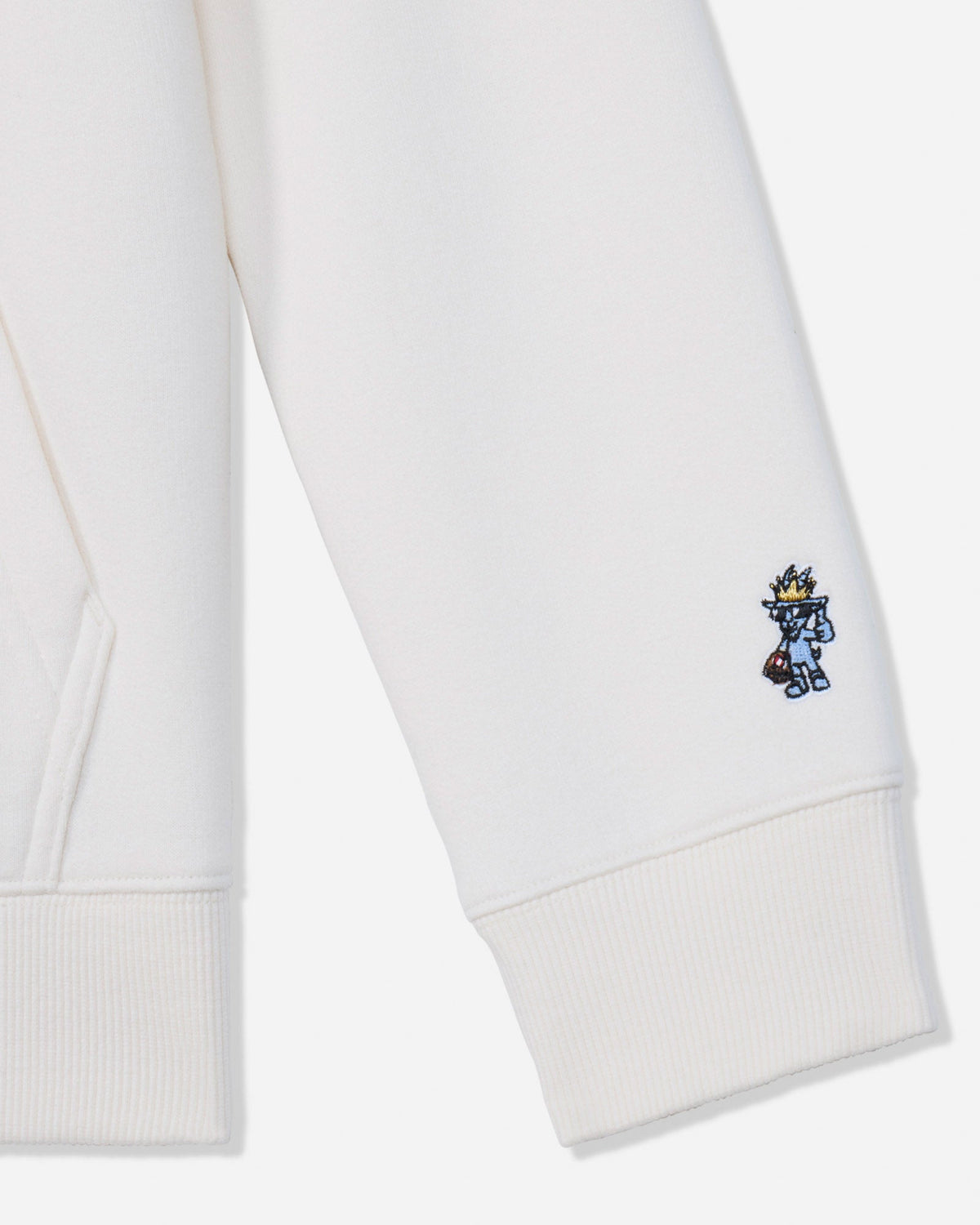 Close-up of a white ribbed cuff on a sweatshirt or hoodie, featuring a small embroidered blue and yellow character on the lower cuff.