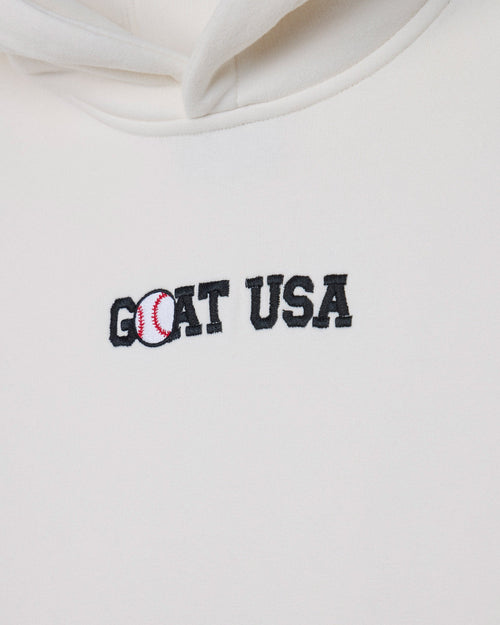 Close-up of a white hoodie featuring an embroidered 'GOAT USA' logo on the chest, with the letter 'O' stylized as a baseball.
