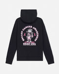 A black hooded sweatshirt shown from the back, featuring a large pink and white graphic print with a cartoon goat character, breast cancer awareness ribbons, and the text 'GOAT USA'.