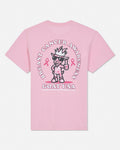 A light pink short-sleeve t-shirt shown from the back, featuring a large graphic print of a cartoon goat wearing sunglasses and a hat, surrounded by the text 'BREAST CANCER AWARENESS' and 'GOAT USA' with pink ribbons.