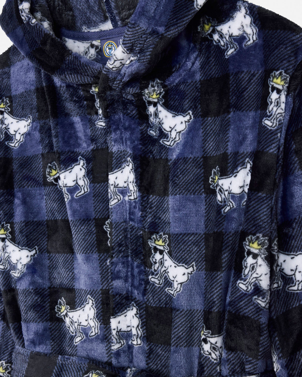 Close-up of a hooded fleece shirt in a navy and black buffalo plaid pattern, featuring a repeating print of white cartoon goats wearing small gold crowns.