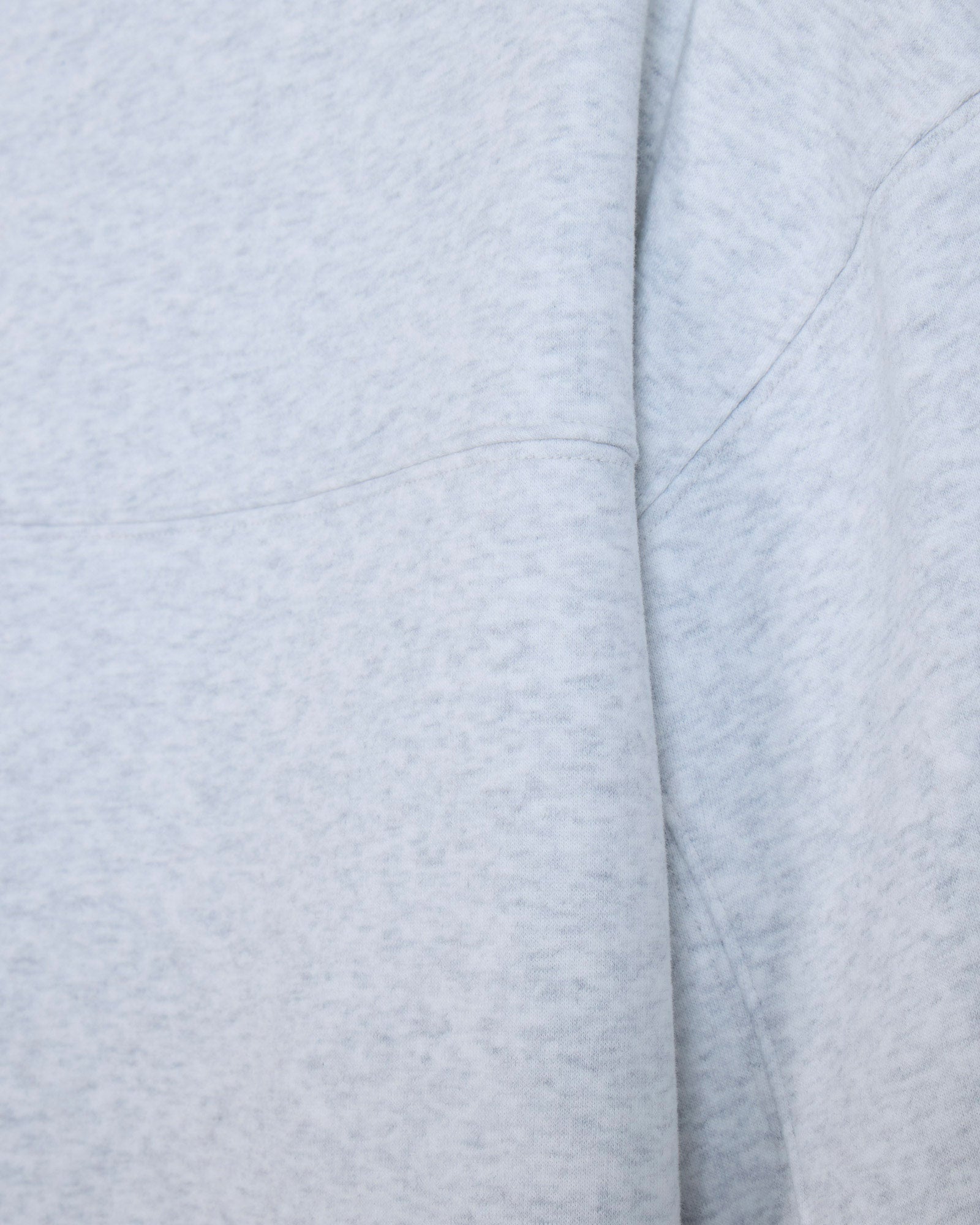 Close-up of a light heather gray fabric with soft folds and stitched seams.