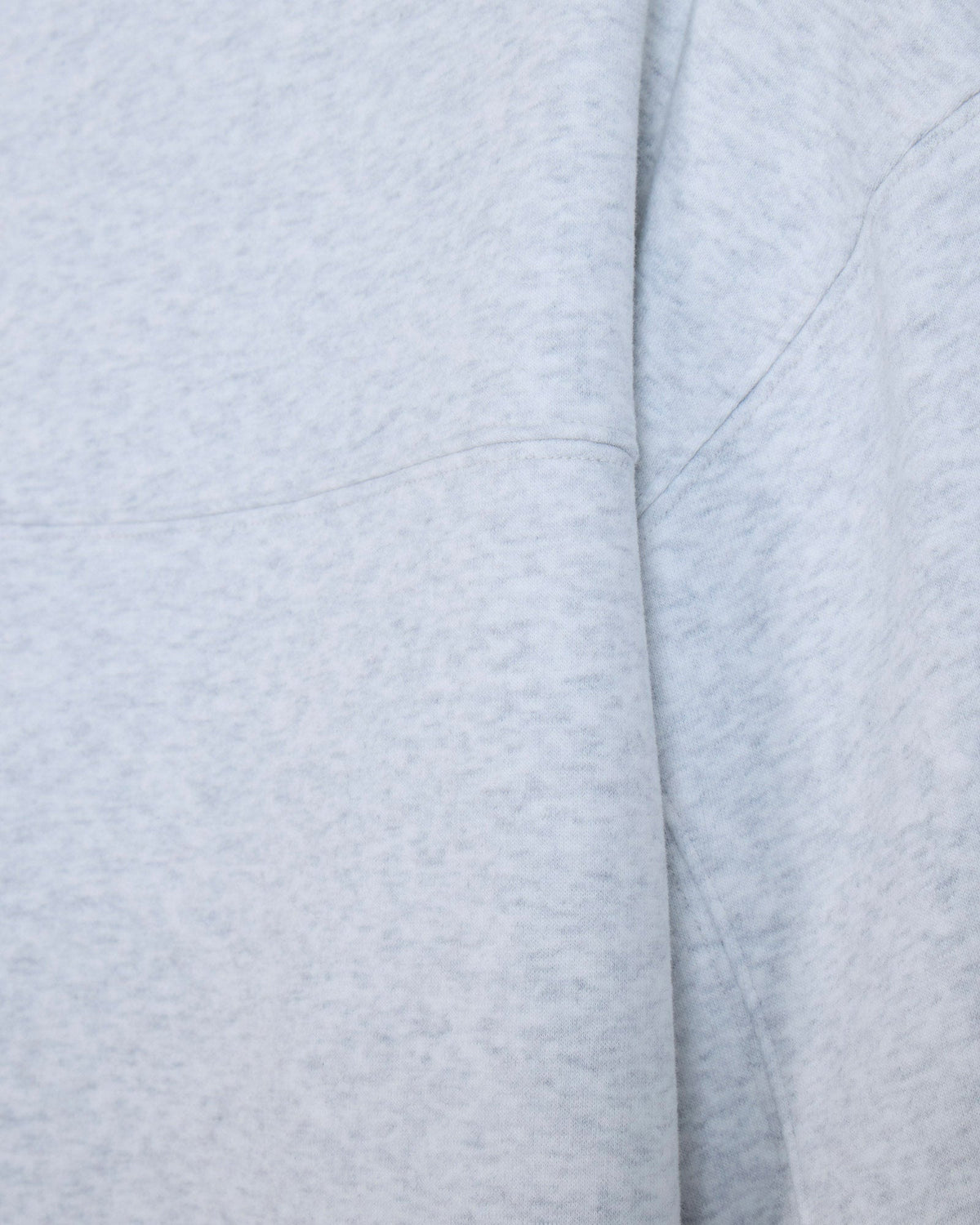 Close-up of a light heather gray fabric with soft folds and stitched seams.