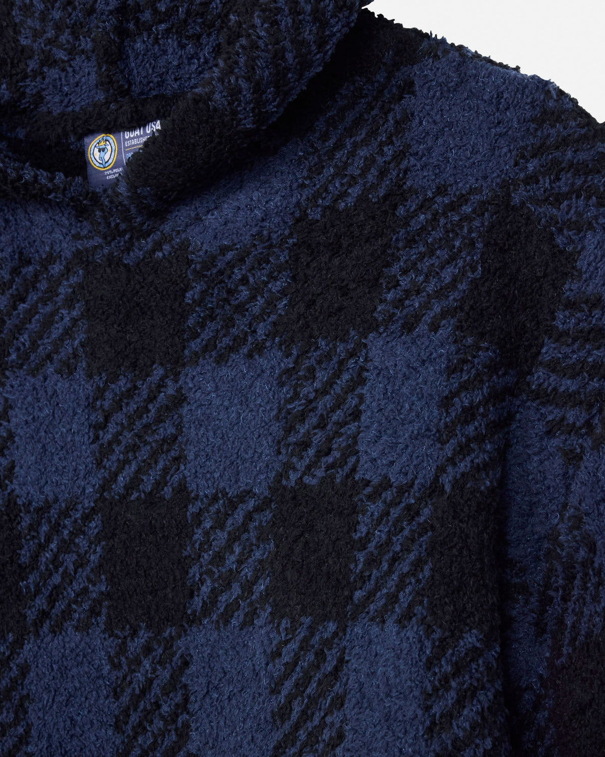 Close-up of a plush fleece jacket with a navy blue and black buffalo plaid pattern, featuring a sherpa-lined collar.