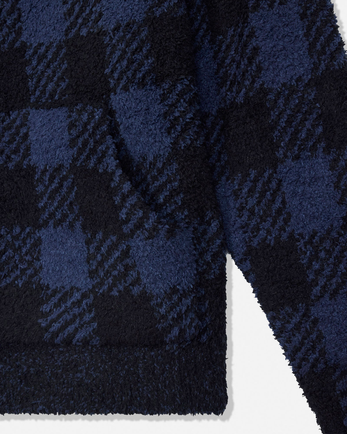 Close-up of a plush fleece fabric with a navy blue and black buffalo plaid pattern, showing the soft texture and ribbed hem.