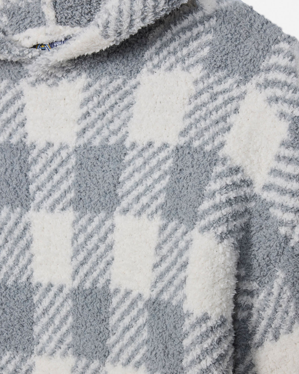 Close-up of a plush fleece garment with a gray and white check pattern, showing the soft textured fabric and part of a hood.