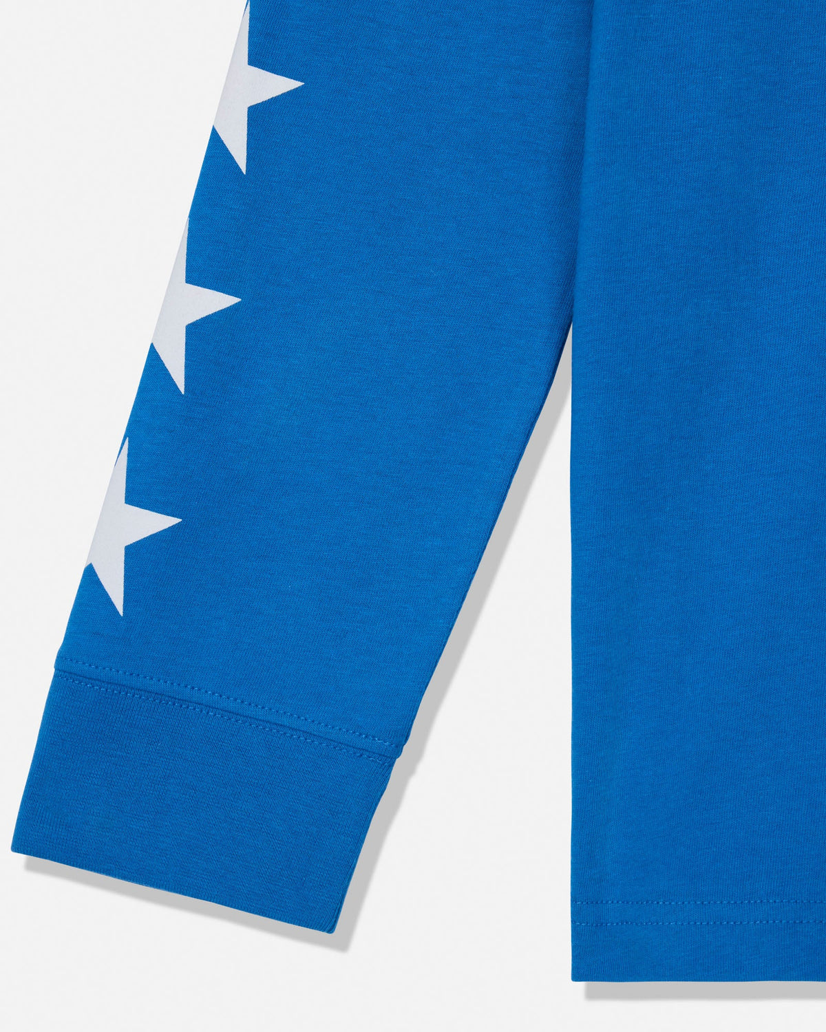 Close-up of a bright blue garment sleeve with a vertical white star graphic and ribbed cuff, shown against a light neutral background.