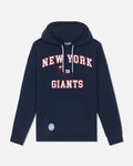 A navy blue pullover hoodie featuring 'NEW YORK GIANTS' printed in white varsity-style letters with red outlines on the chest, accompanied by the team's logo. The hoodie includes white drawstrings and a front kangaroo pocket, shown against a light gray background.