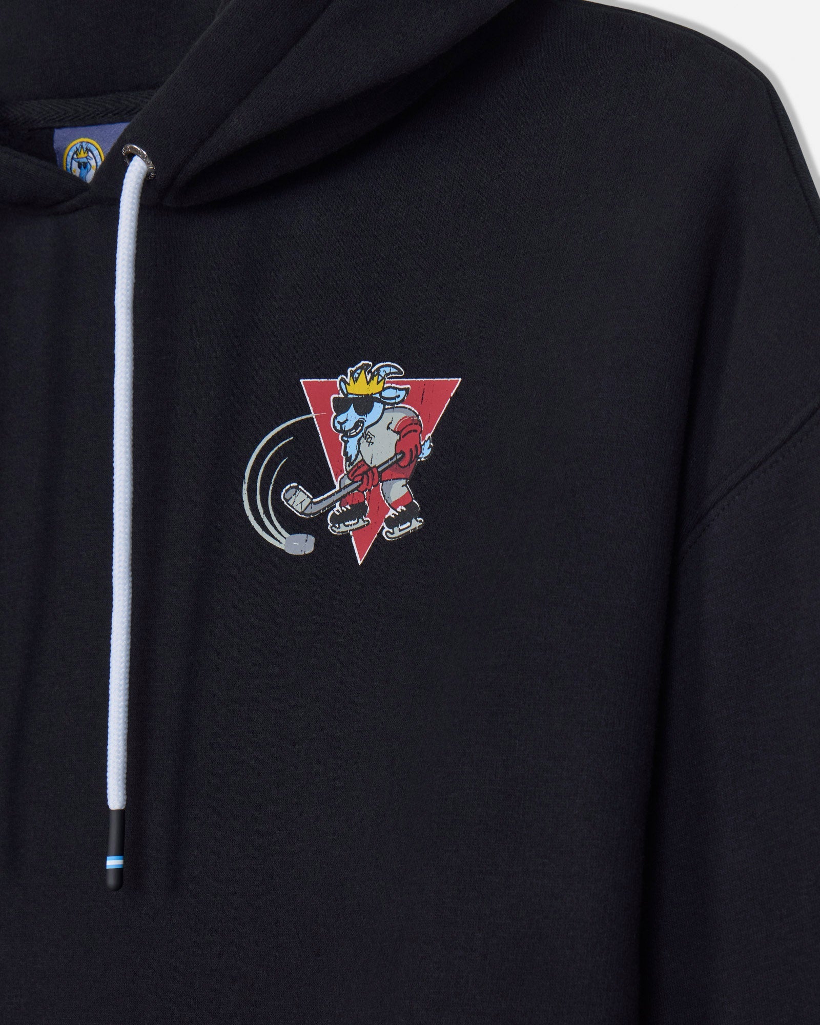Close-up of a black pullover hoodie with a white drawstring and a colorful cartoon graphic on the left chest, featuring a red triangle and a character in a yellow crown.