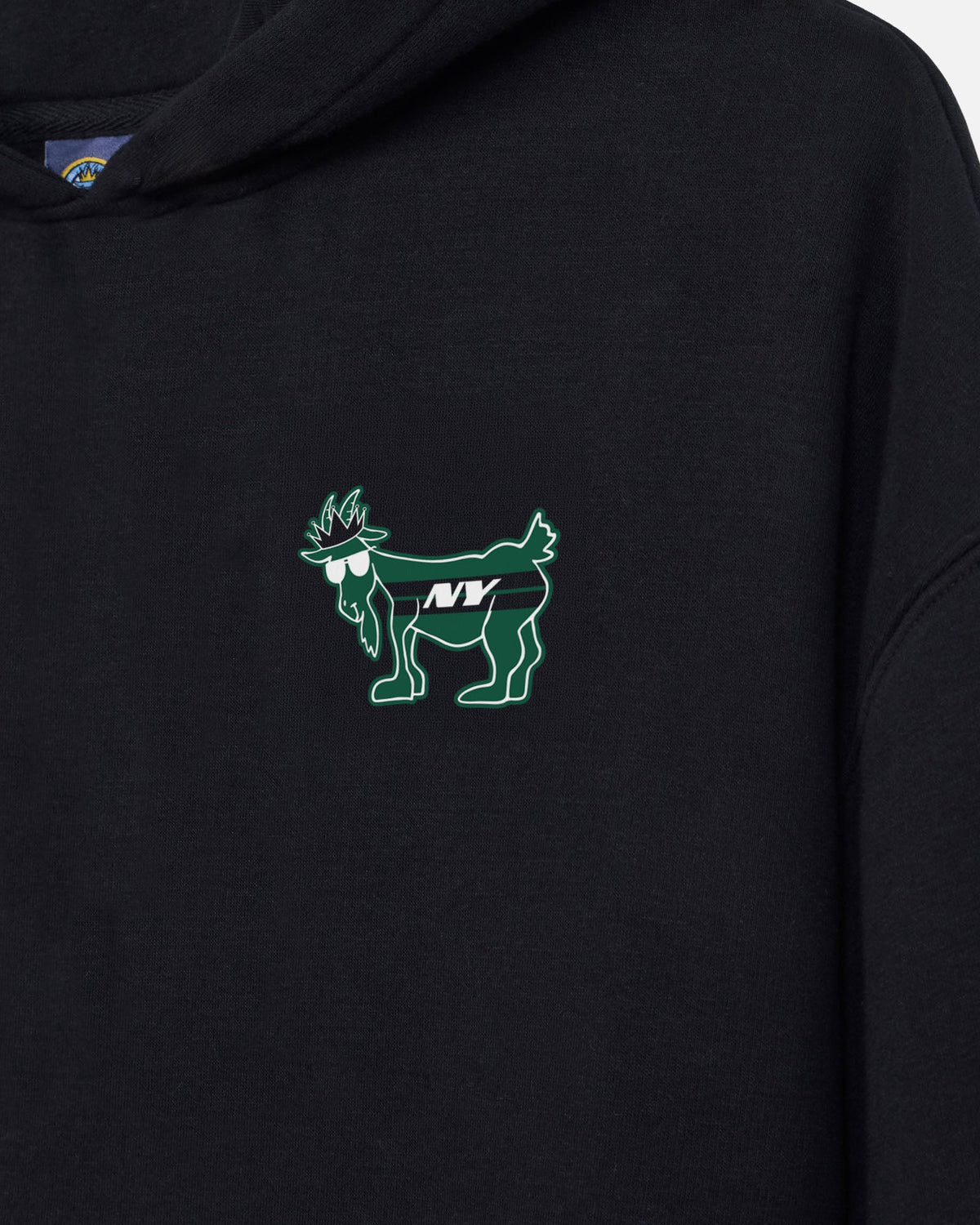 Close-up of a black hoodie featuring a green and white embroidered goat graphic on the left chest with the letters 'NY' in the center.