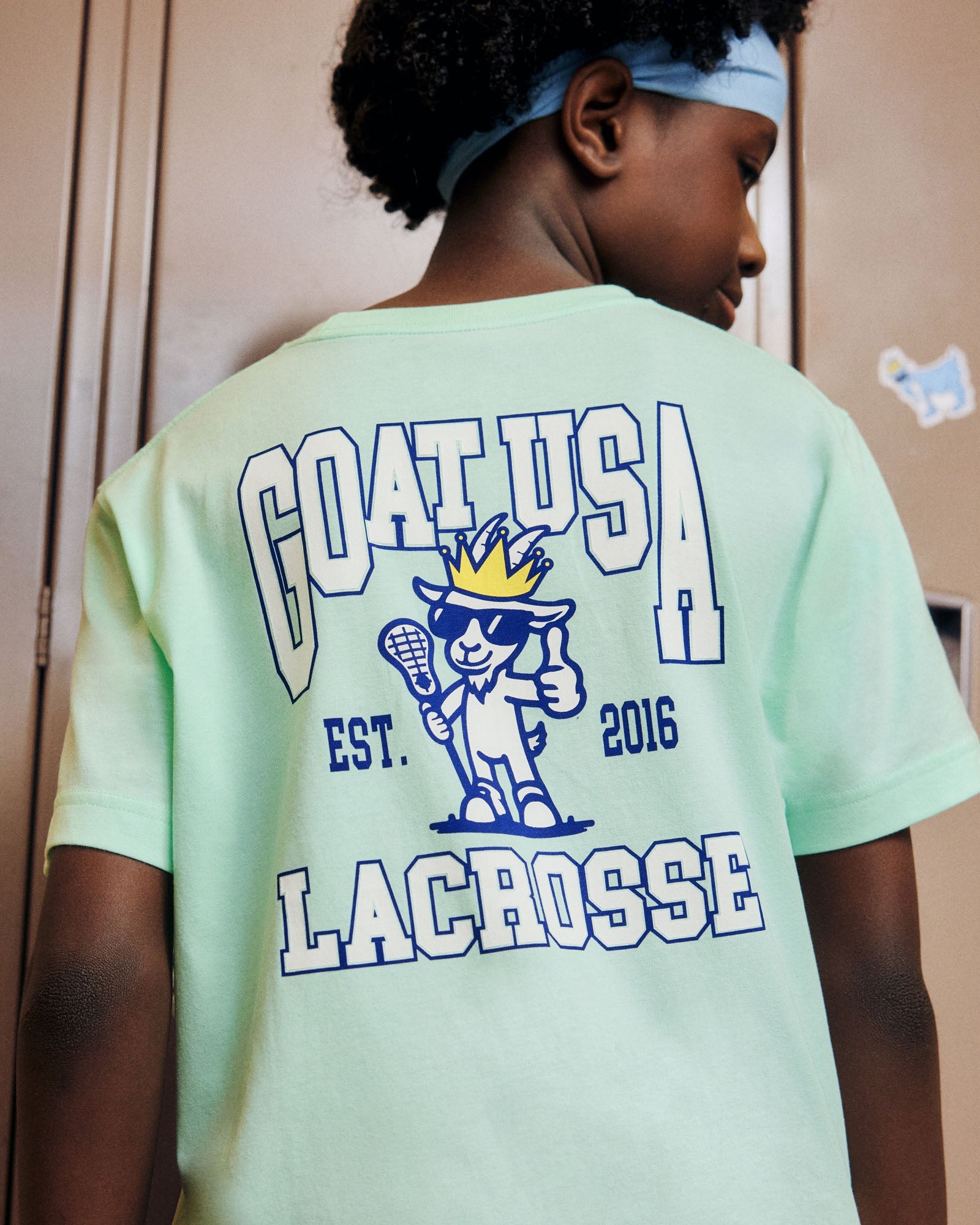 Person wearing a light green t-shirt with 'GOAT USA Lacrosse' text and logo.