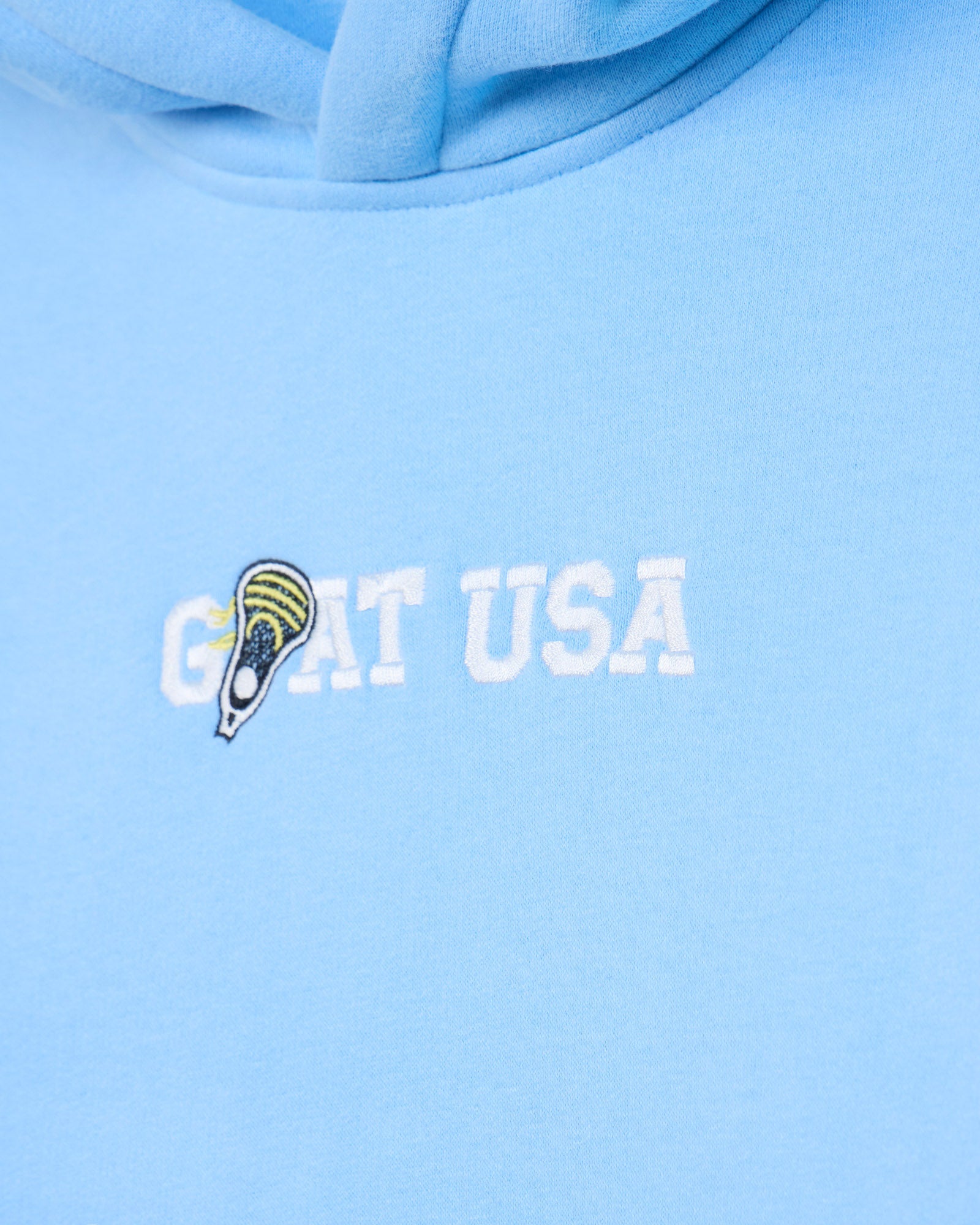 Close-up of 'GOAT USA' stitching with lacrosse stick on a light blue hoodie