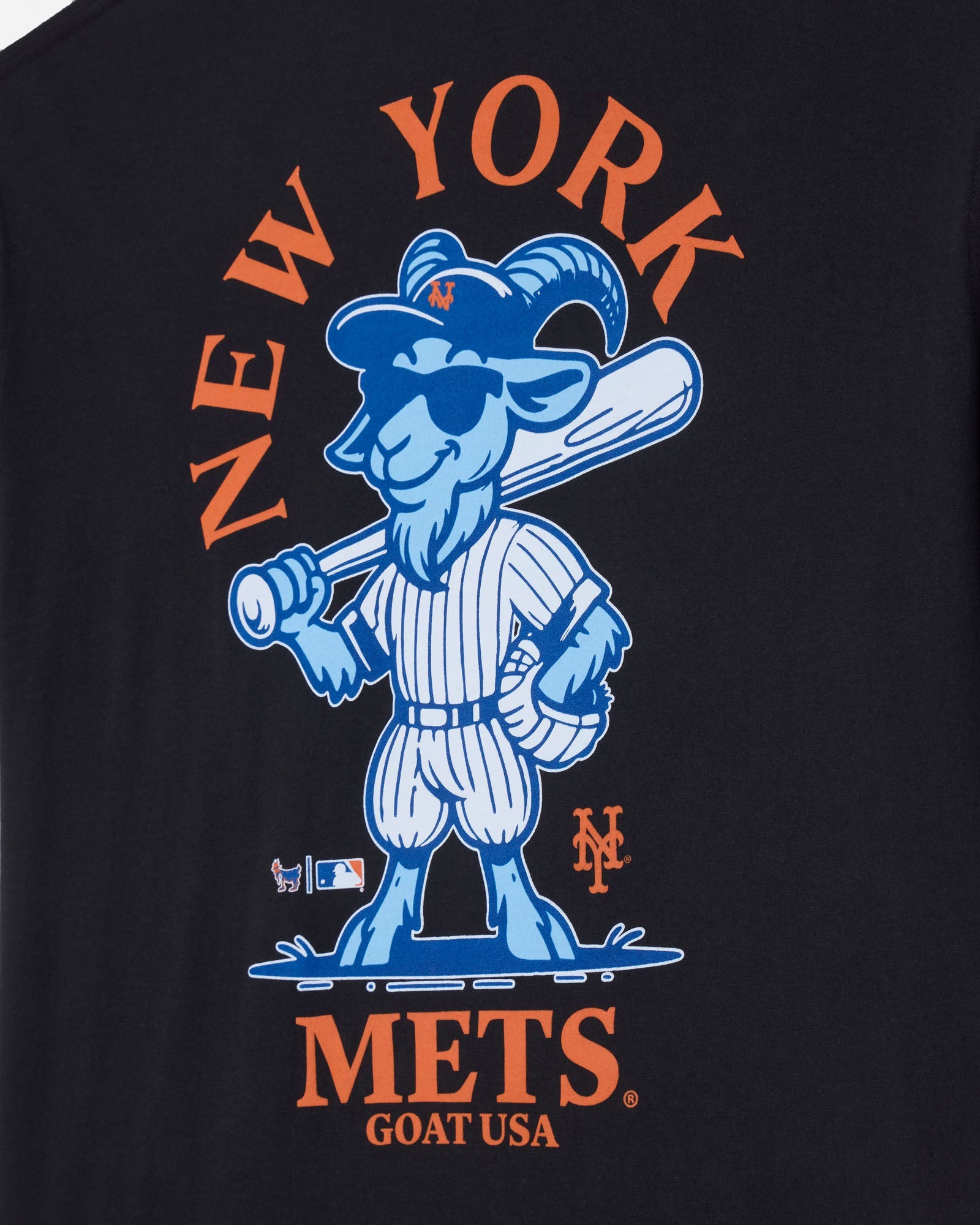 Close-up of a black T-shirt featuring a large New York Mets graphic print. The design shows the blue goat mascot holding a baseball bat, with orange text reading 'NEW YORK' above and 'METS GOAT USA' below.