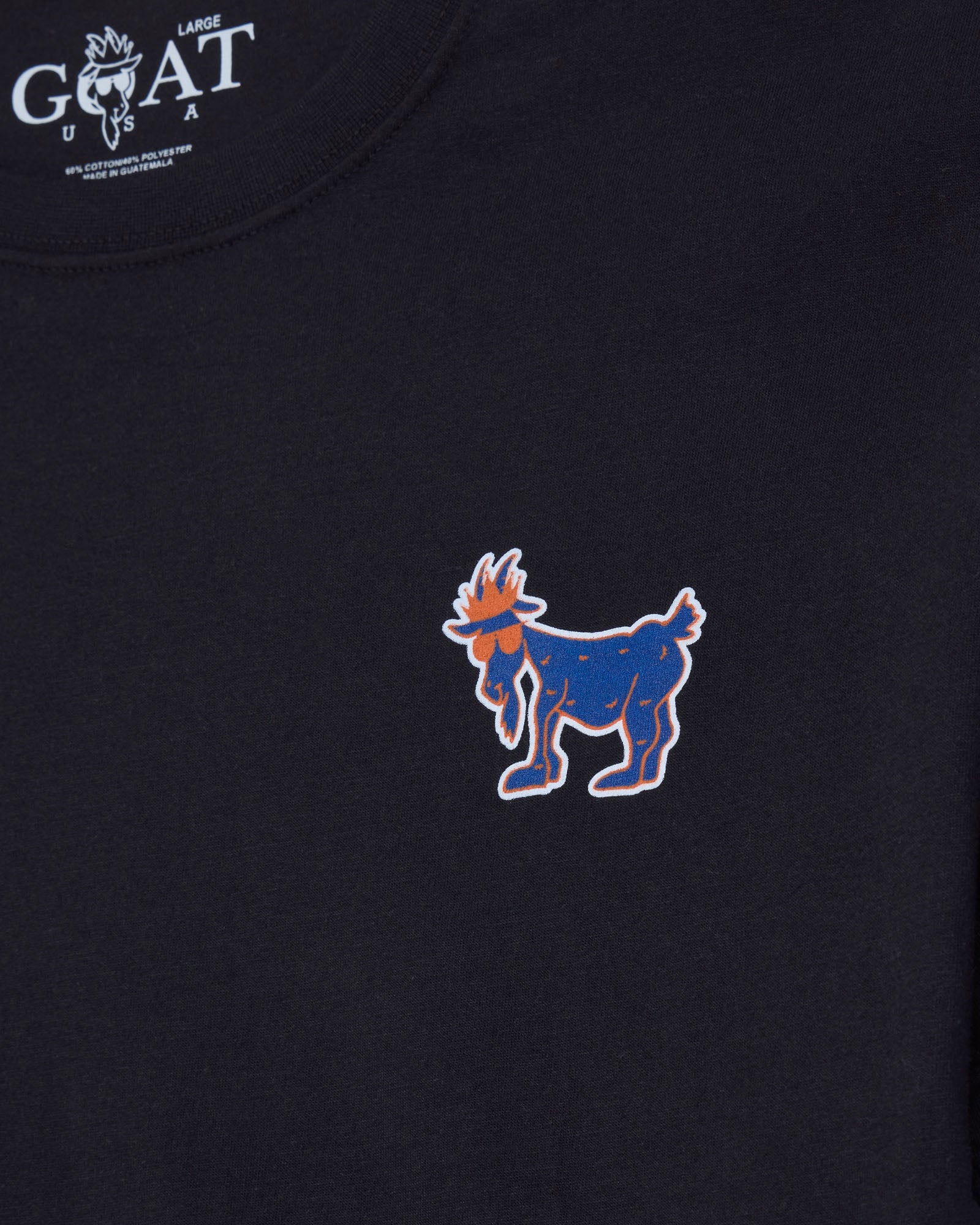 Close-up of a black long-sleeve t-shirt featuring a blue and orange embroidered goat graphic on the left chest, with a white 'GOAT USA LARGE' logo printed inside the collar.