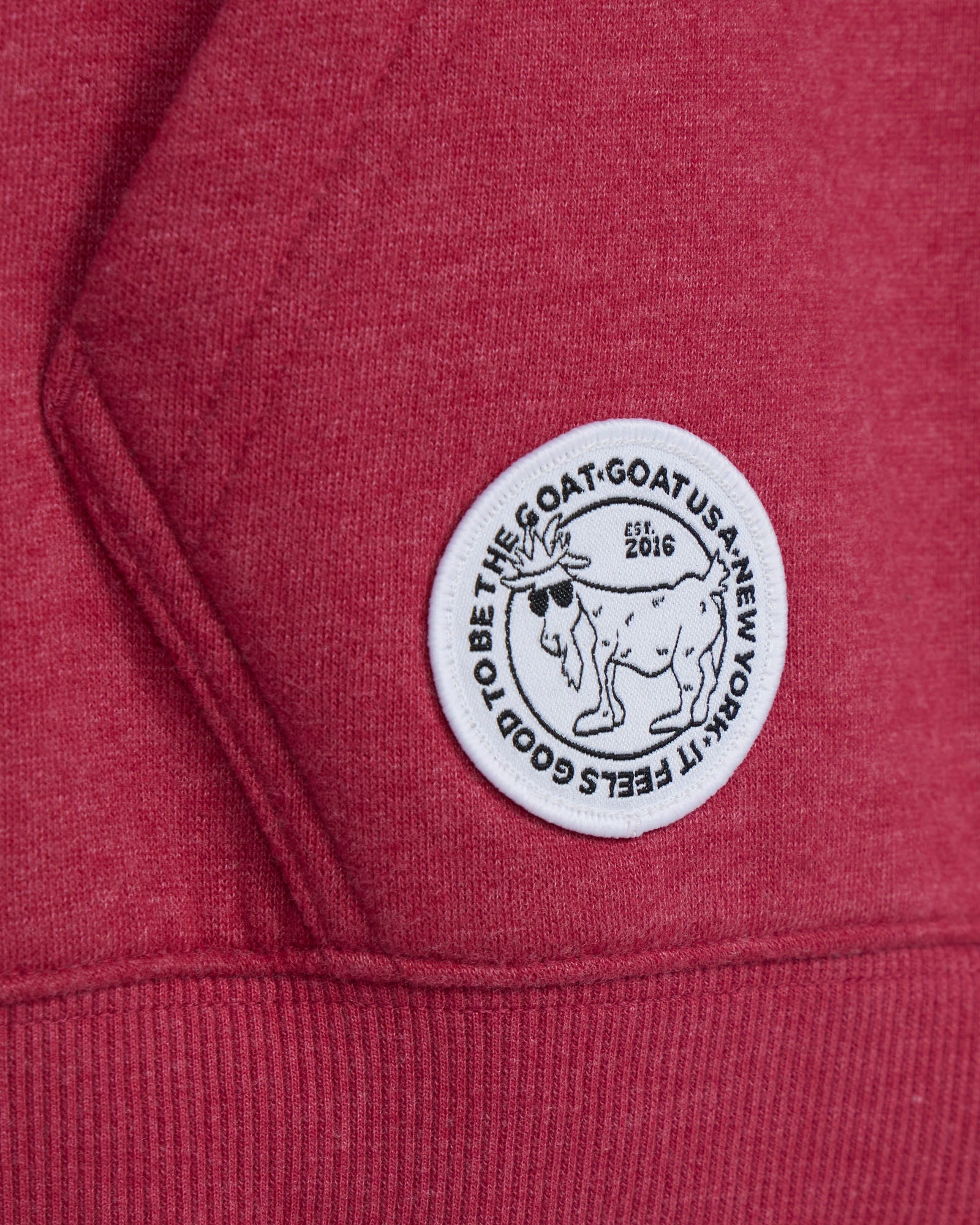 Close-up of a red hoodie with a white logo on the chest.