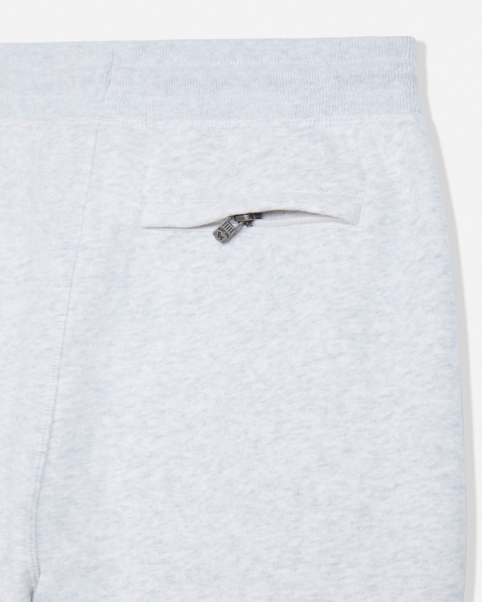 Close-up of light heather gray sweatpants showing a side pocket with a small silver zipper pull.#color_pale-gray