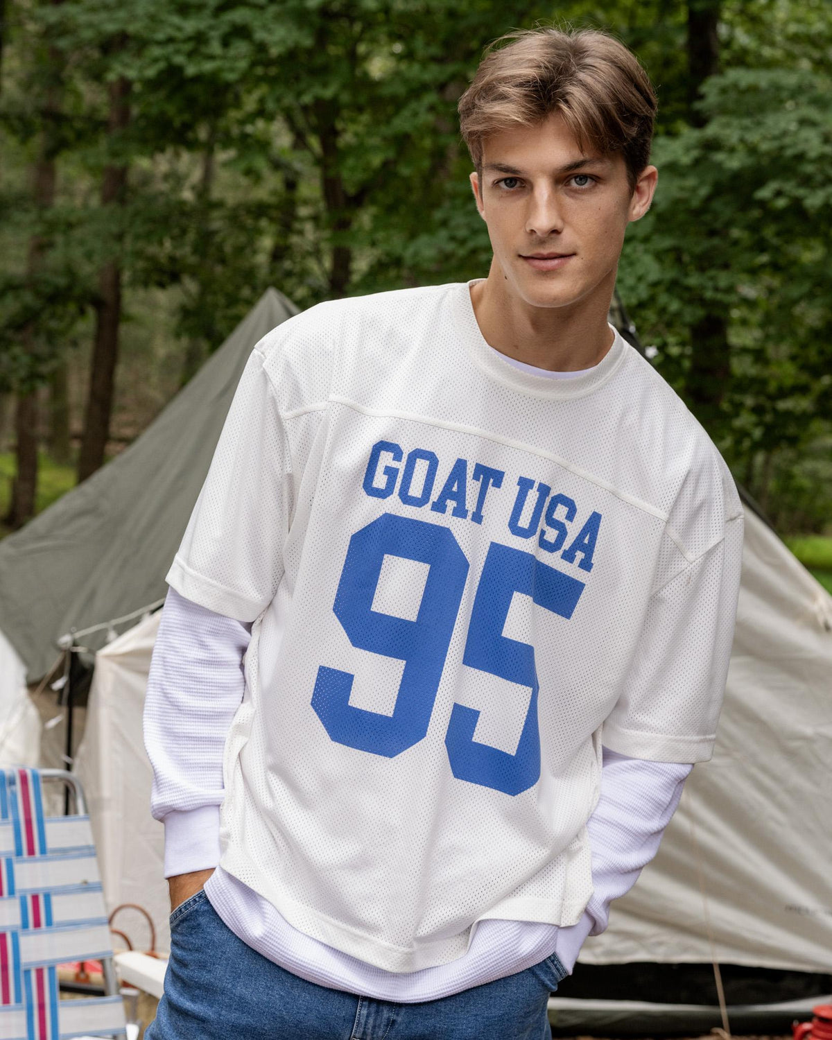 Person wearing a white sweatshirt with 'GOAT USA 95' text in a forest setting