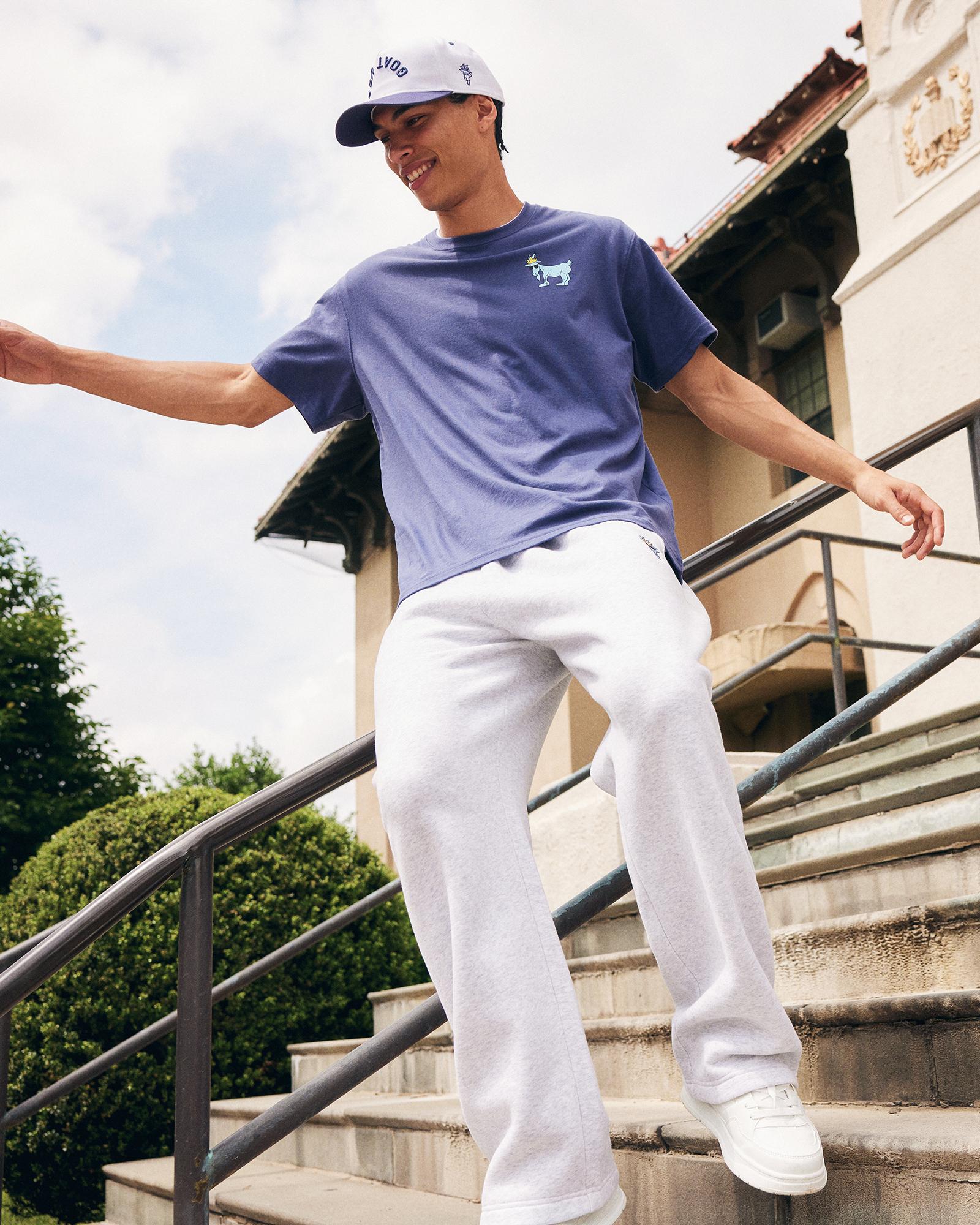 Person wearing a blue t-shirt and gray pants standing on steps outdoors#color_gray