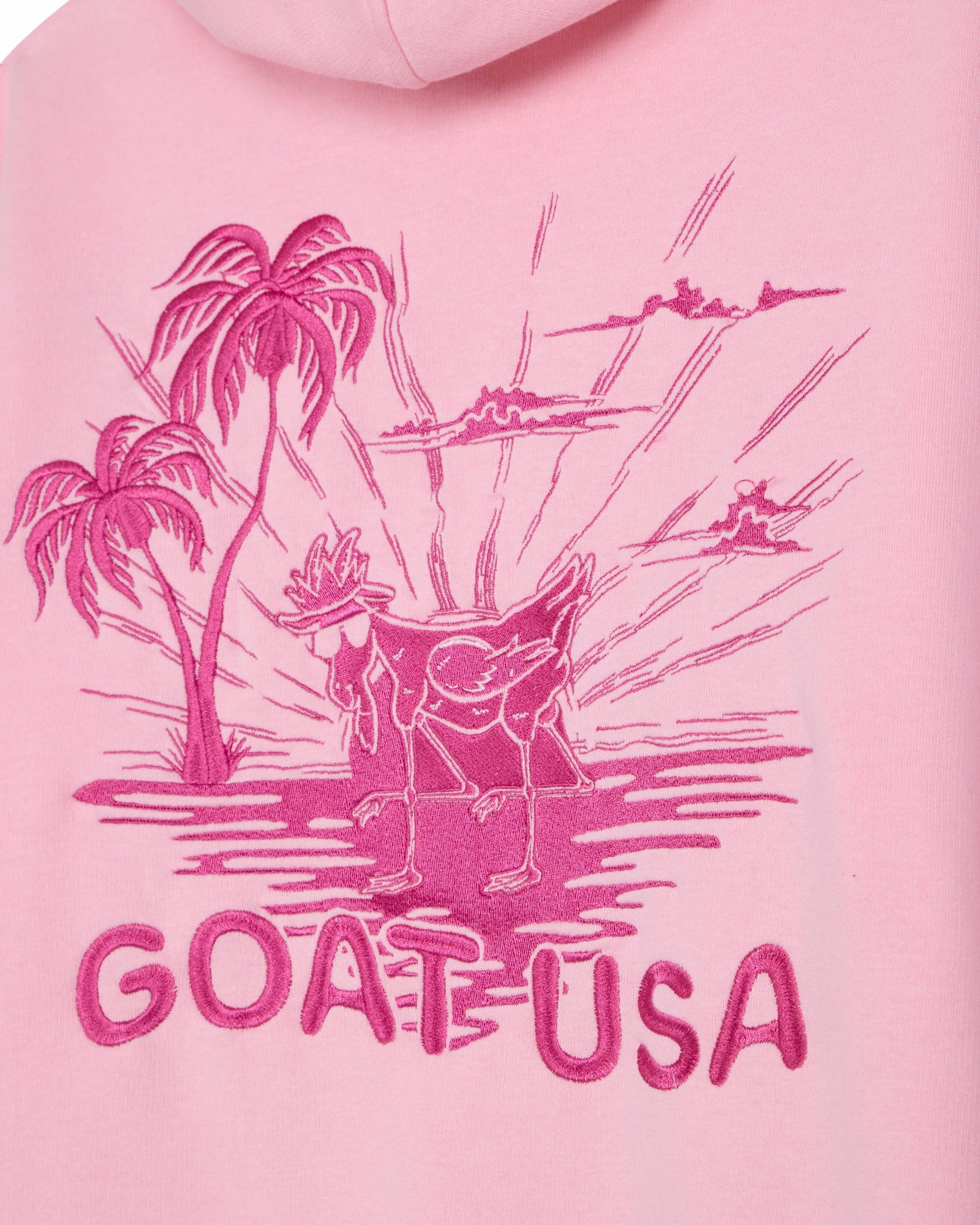 Pink hoodie with a graphic of a goat and palm trees, labeled 'GOAT USA', on a pink background.#color_light-pink