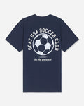 A navy blue short-sleeve t-shirt with a white graphic on the back featuring a soccer ball and the text 'GOAT USA SOCCER CLUB' and 'be the greatest'.