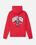 A red pullover hoodie shown from the back, featuring a large graphic print of the text 'GOAT USA' in white with black outlines and a cartoon goat character wearing a Santa hat and holding a gift. The text 'EST. 2016'