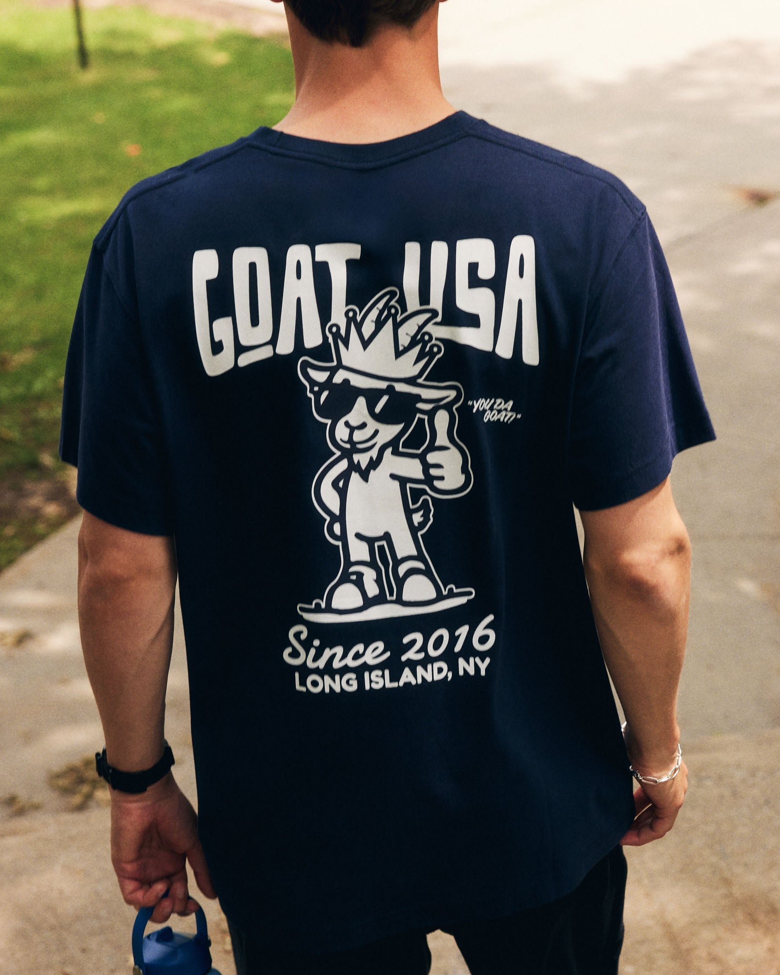 Person wearing a navy blue t-shirt with 'GOAT USA' logo and text.
