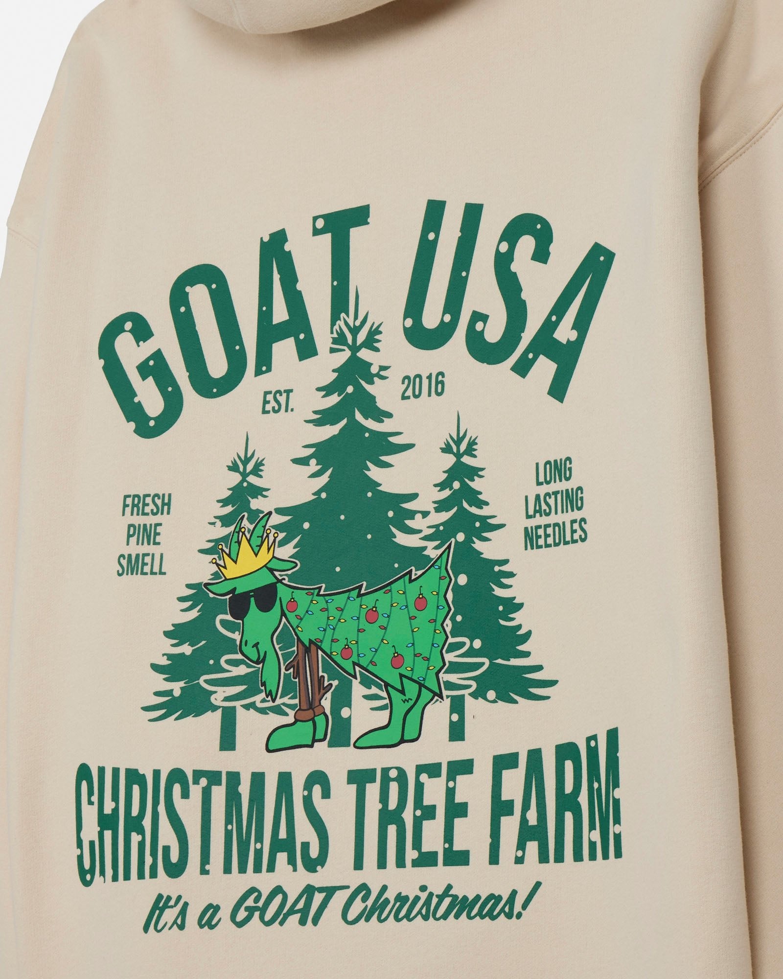 Beige hoodie with green graphic design featuring a goat and Christmas trees, labeled 'GOAT USA Christmas Tree Farm'.