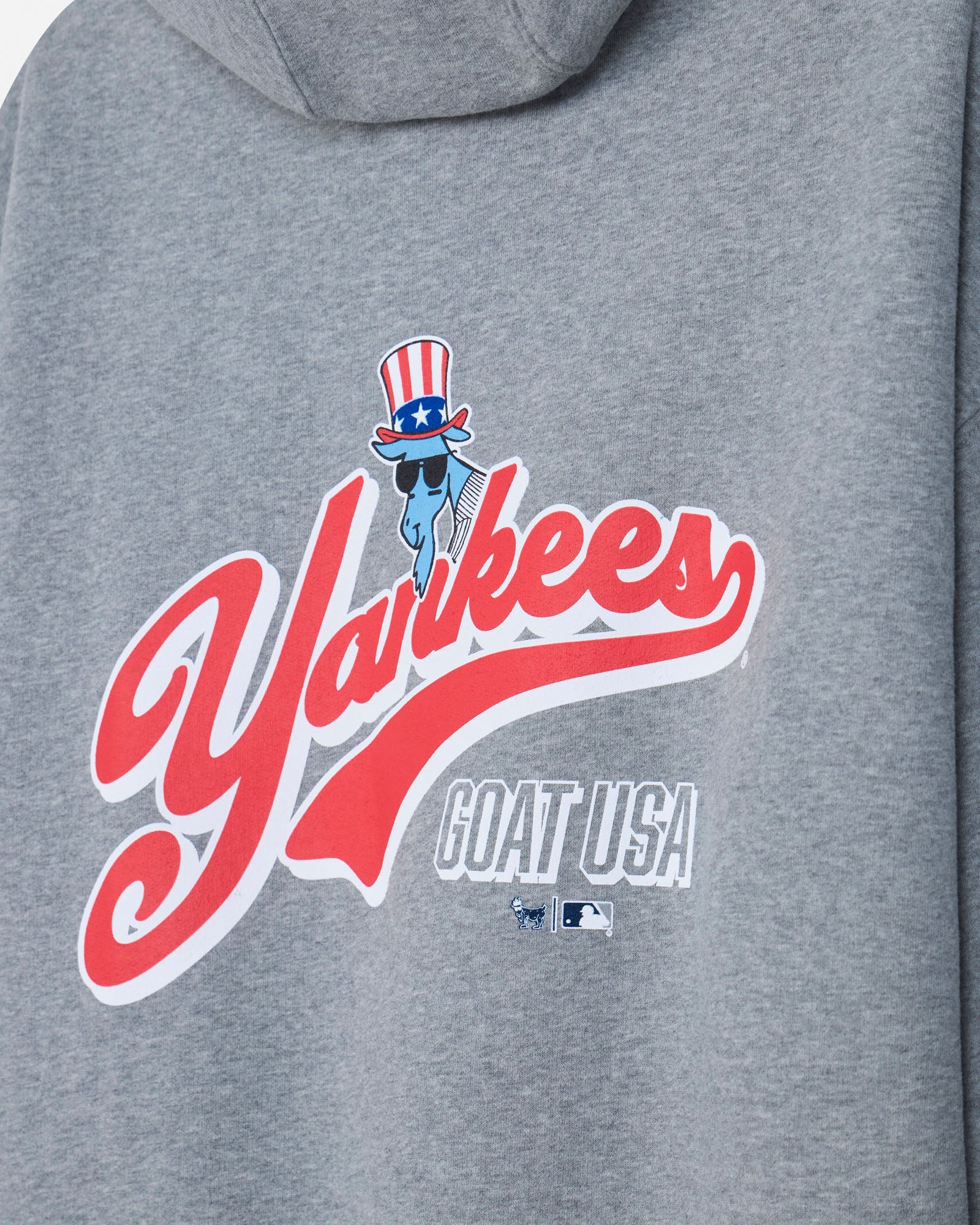 Close-up of a heather gray hoodie featuring a large red, white, and blue Yankees graphic with a cartoon bat wearing a patriotic top hat and sunglasses, plus the text 'GOAT USA'.