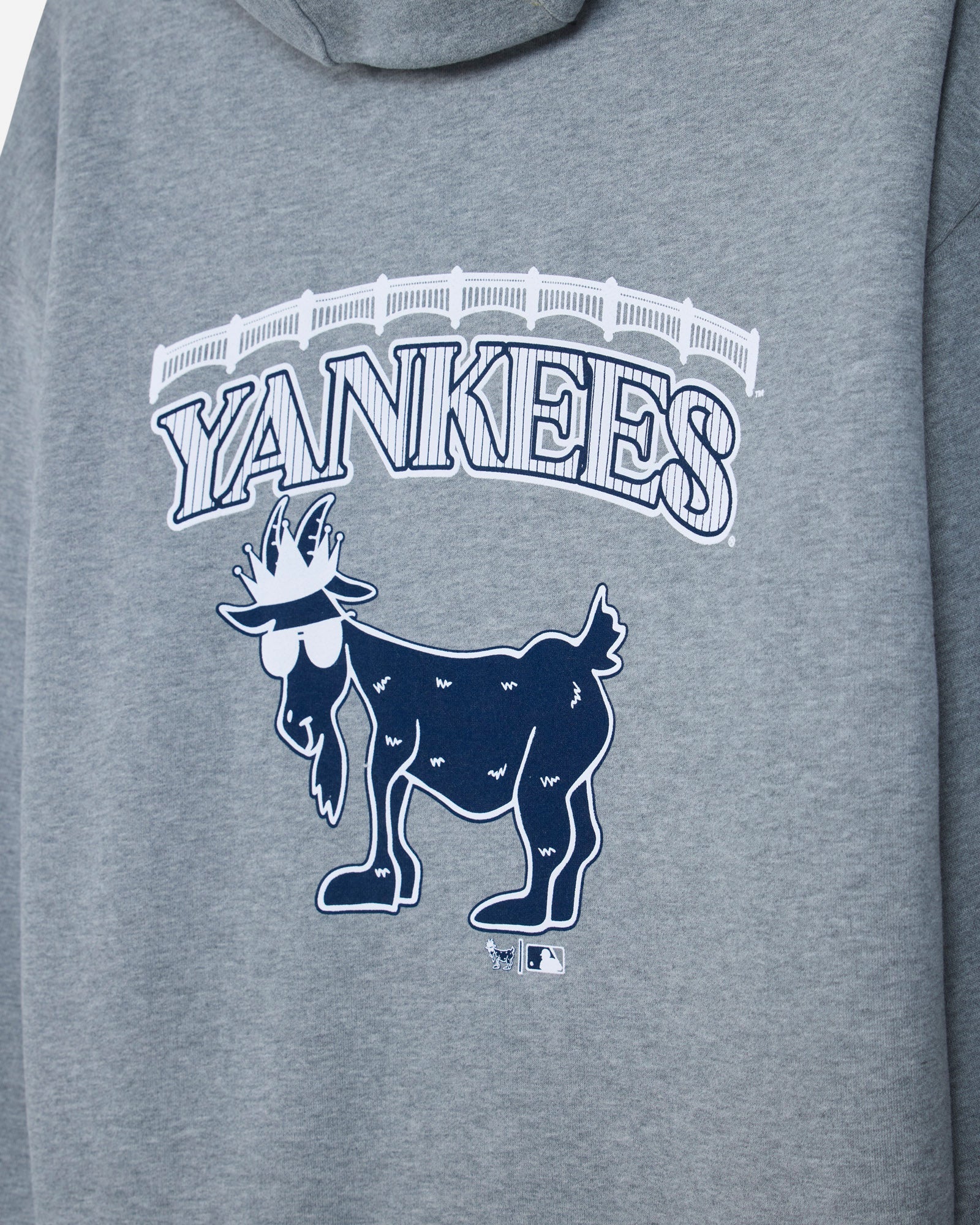 Close-up of a heather gray hoodie featuring a white and navy blue Yankees graphic with the wordmark and a goat logo.#color_gray