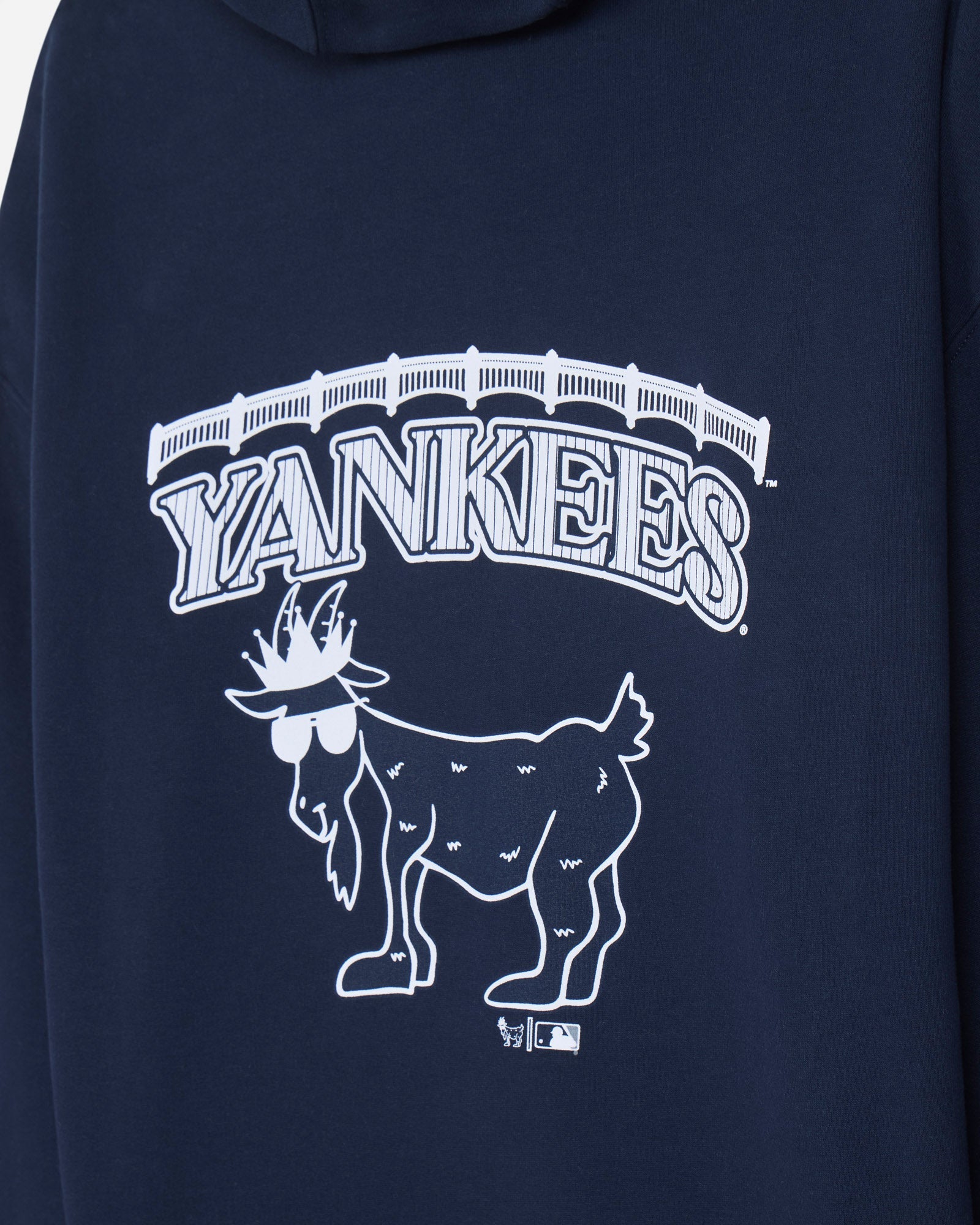 Close-up of a navy blue hoodie featuring a white New York Yankees graphic with the word 'YANKEES' and a stylized goat logo.#color_navy