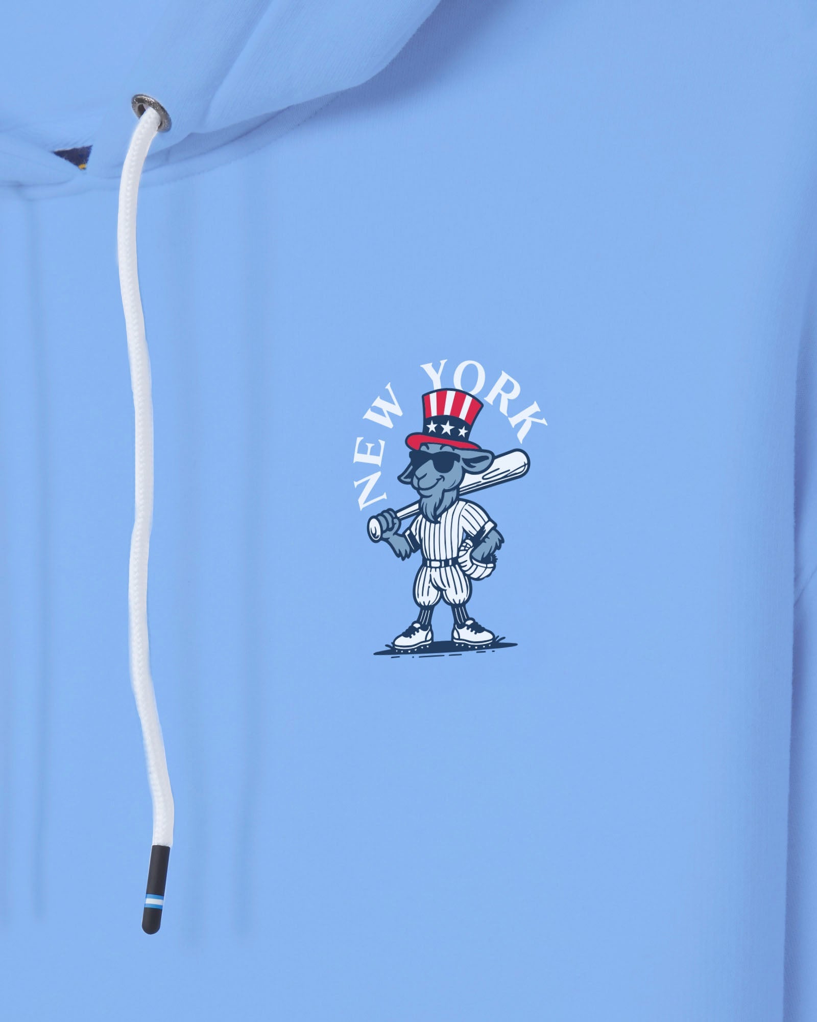 A close-up of a light blue hoodie featuring a cartoon New York baseball character wearing a red, white, and blue Uncle Sam hat, with the text 'NEW YORK' arched above it. A white drawstring is visible on the left side.#color_carolina-blue