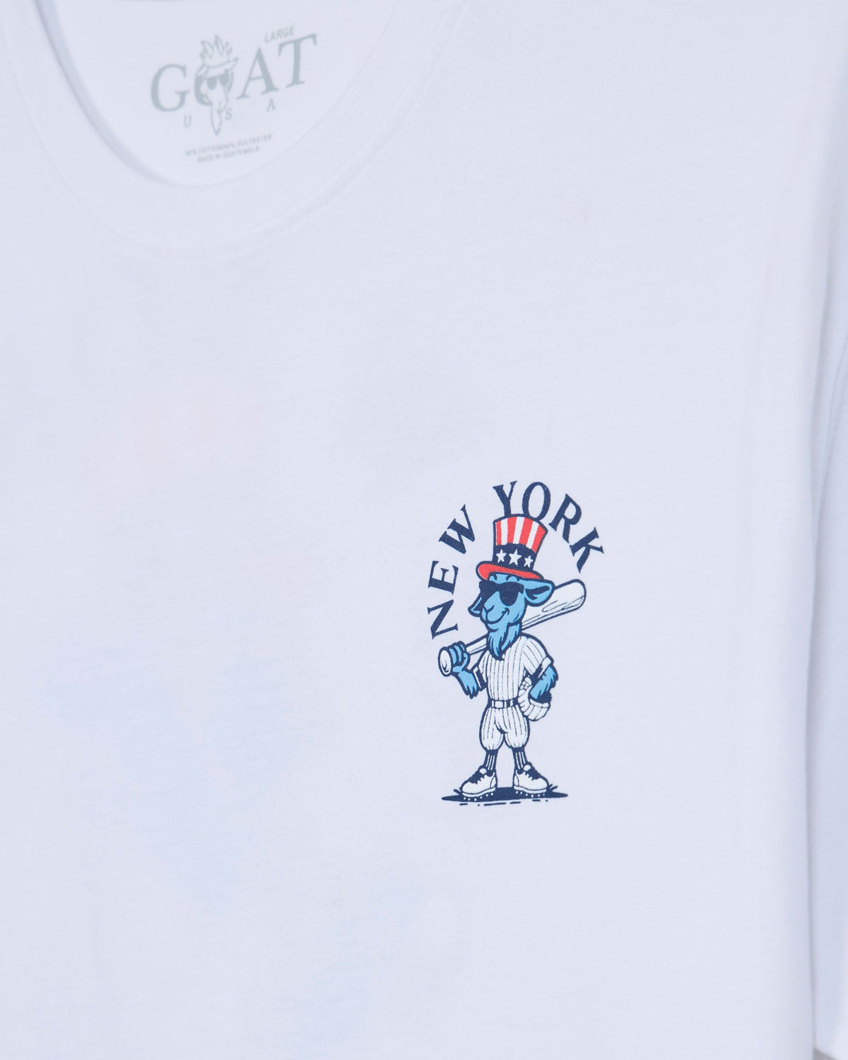 White short-sleeve t-shirt featuring a blue cartoon character wearing a red, white, and blue Uncle Sam top hat, with the text 'NEW YORK' arched above it. The inner neck label shows the brand 'GOAT'.