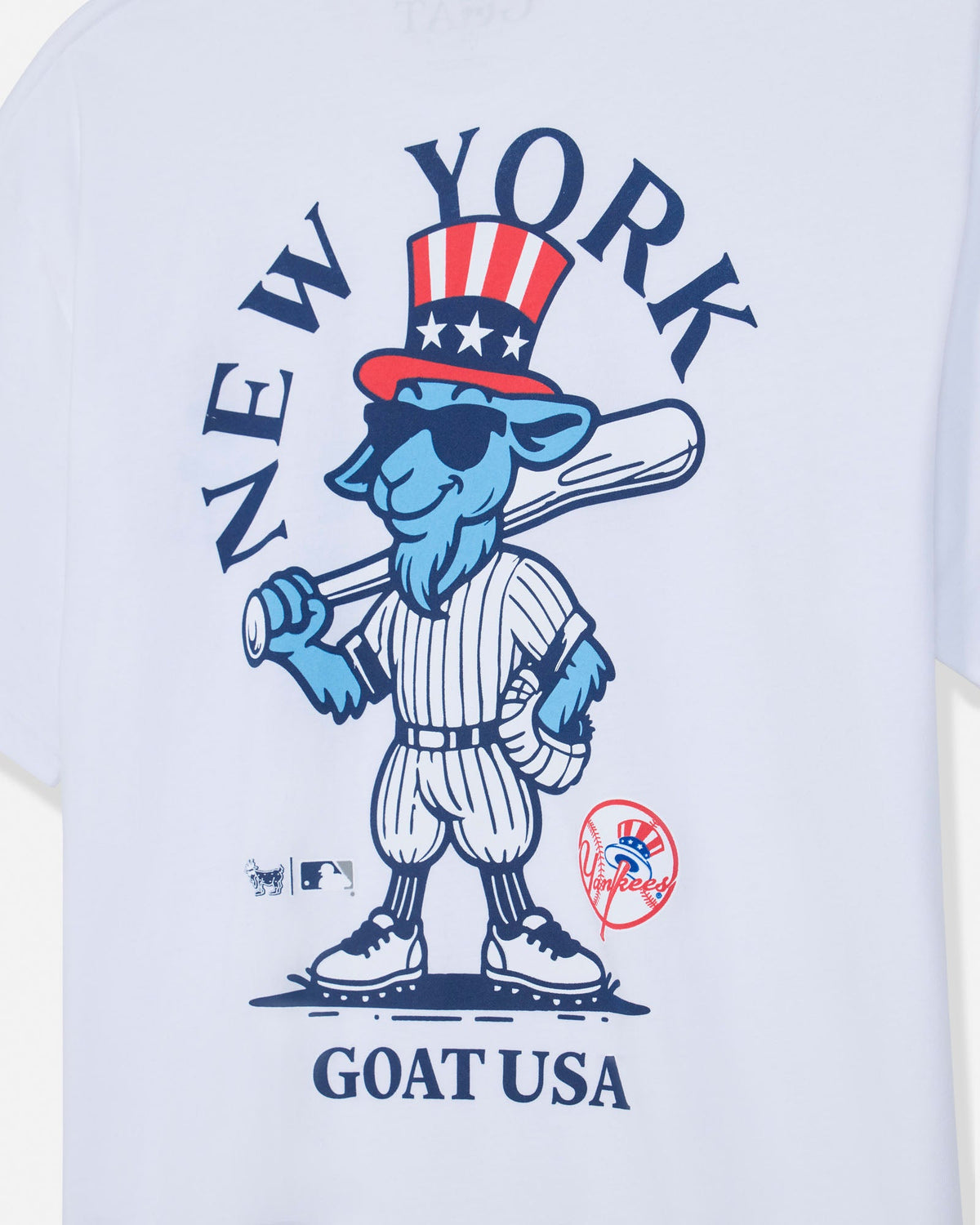 White short-sleeve t-shirt featuring a blue cartoon goat mascot in a baseball uniform with a red, white, and blue top hat. The graphic includes the text 'NEW YORK' arched above and 'GOAT USA' below, with MLB and New York Yankees logos near the bottom.