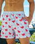 Man with one hand in pocket wearing a bathing suit with a lobster goat pattern