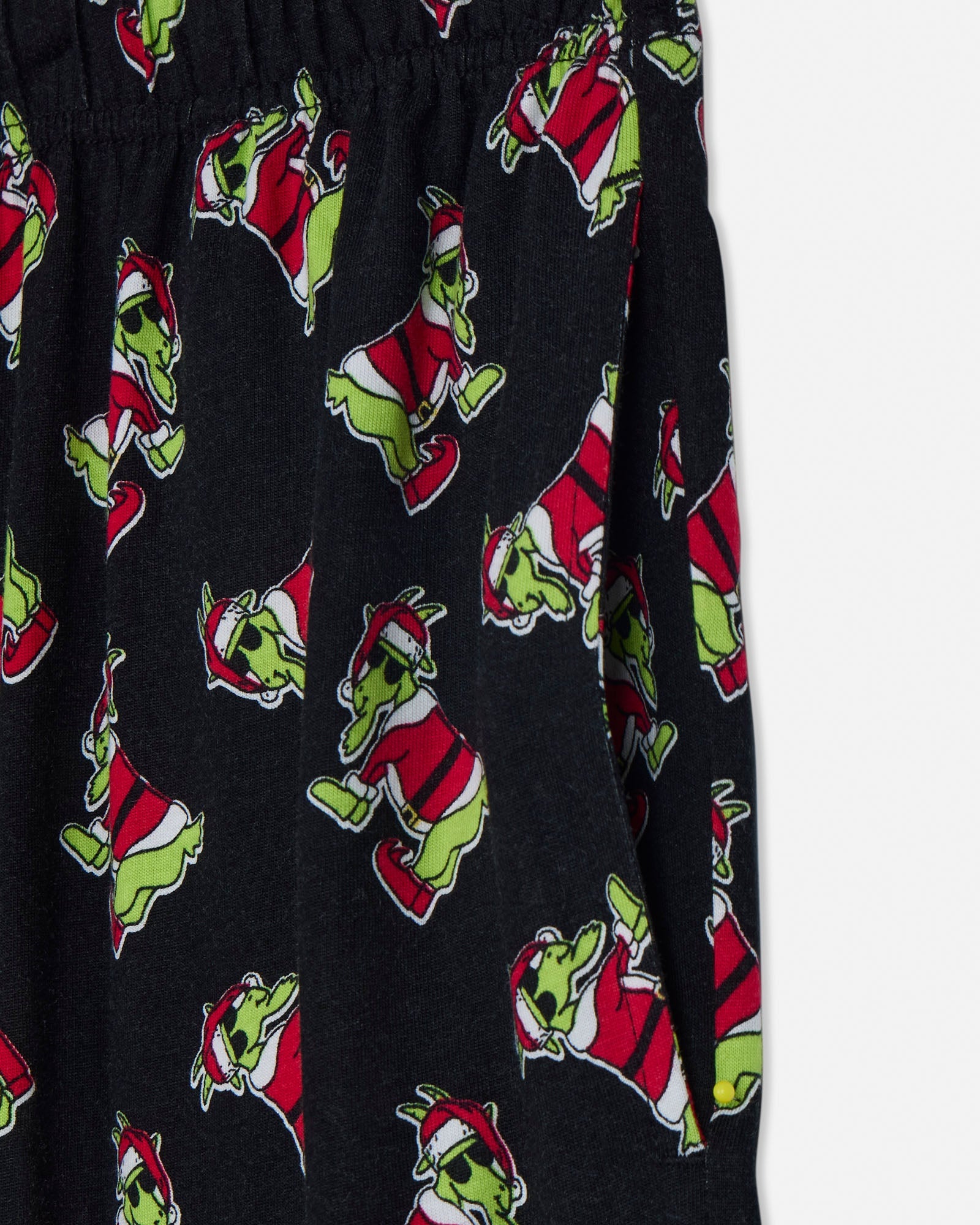 Black pajama pants with green santa pattern on a light gray background