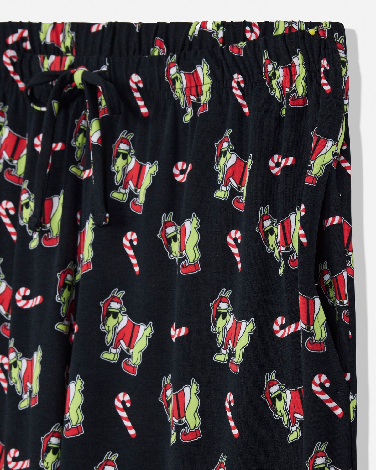 Black holiday-themed lounge pants featuring a repeating pattern of green Santa-clad goat and red-and-white candy canes, with an elastic waistband and drawstring.