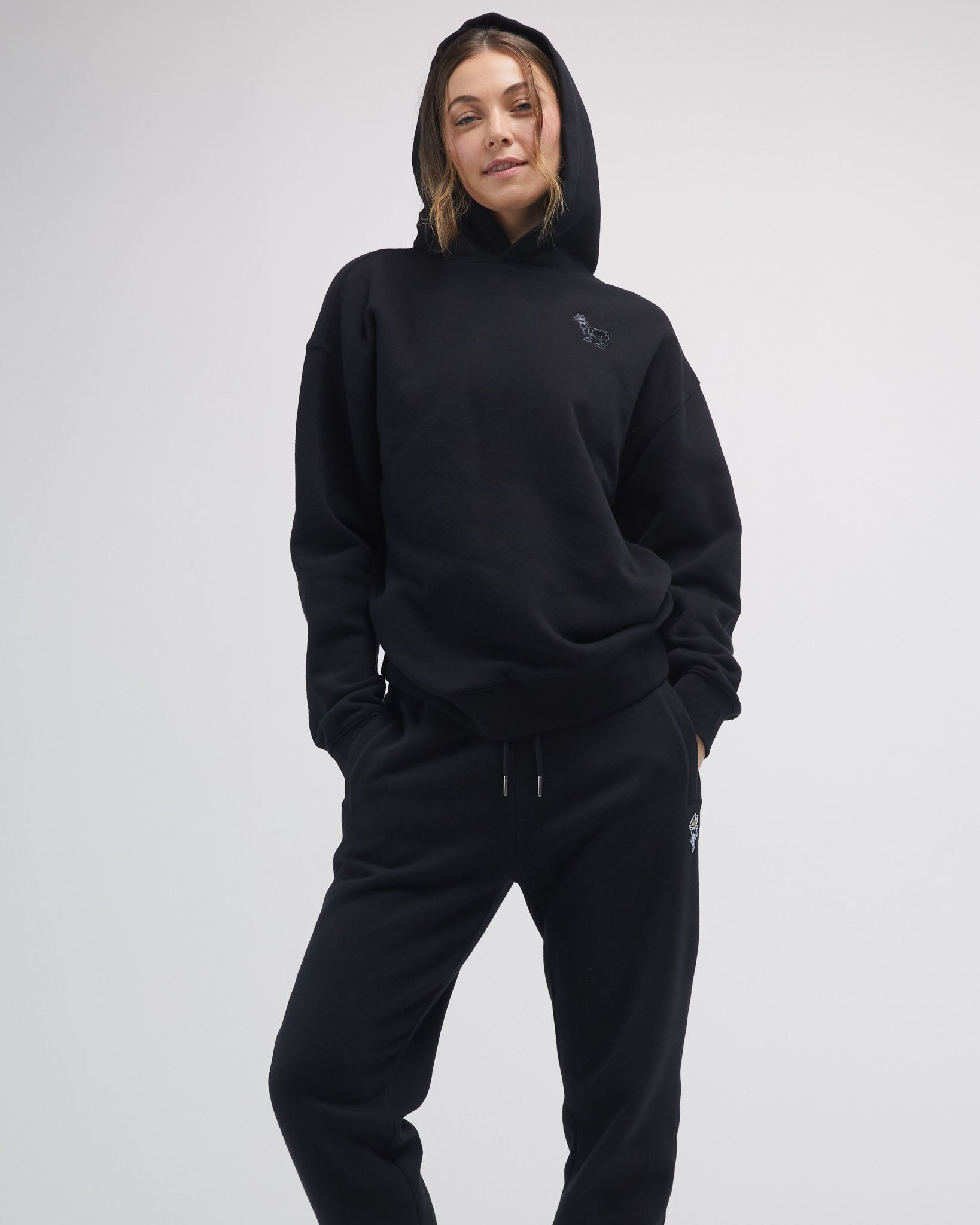 Person wearing a black hoodie and pants on a white background#color_black