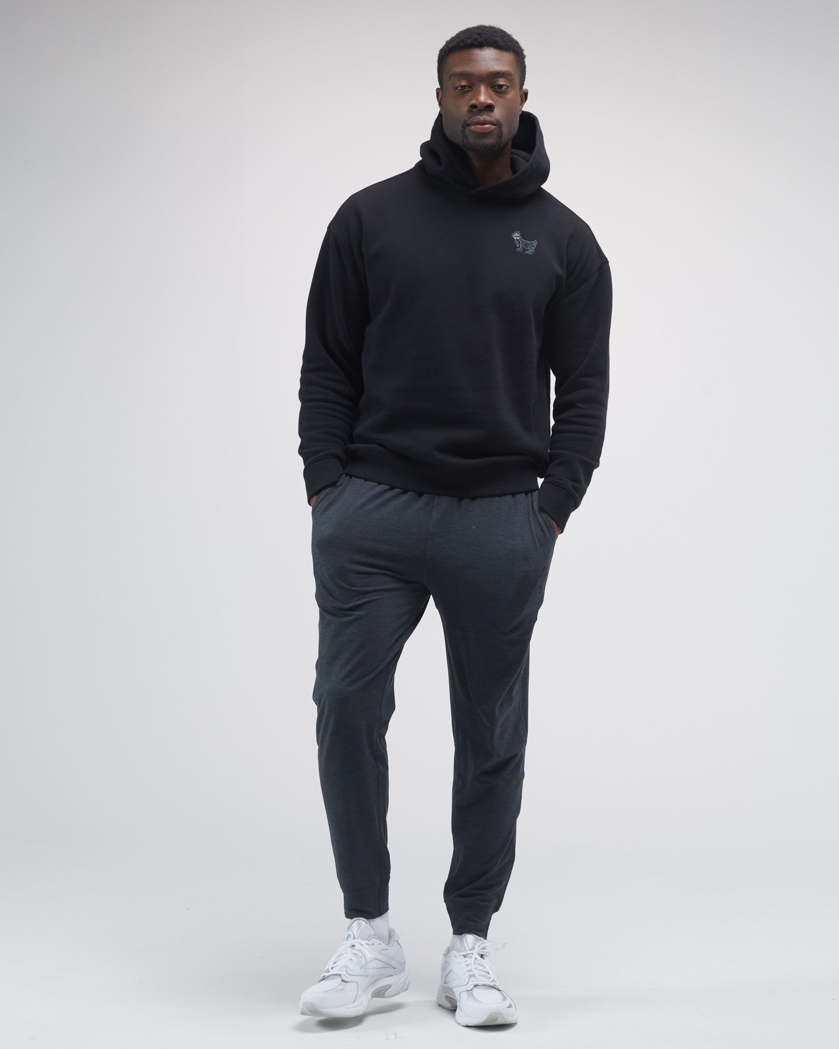 Person wearing a black hoodie and dark pants on a white background#color_black