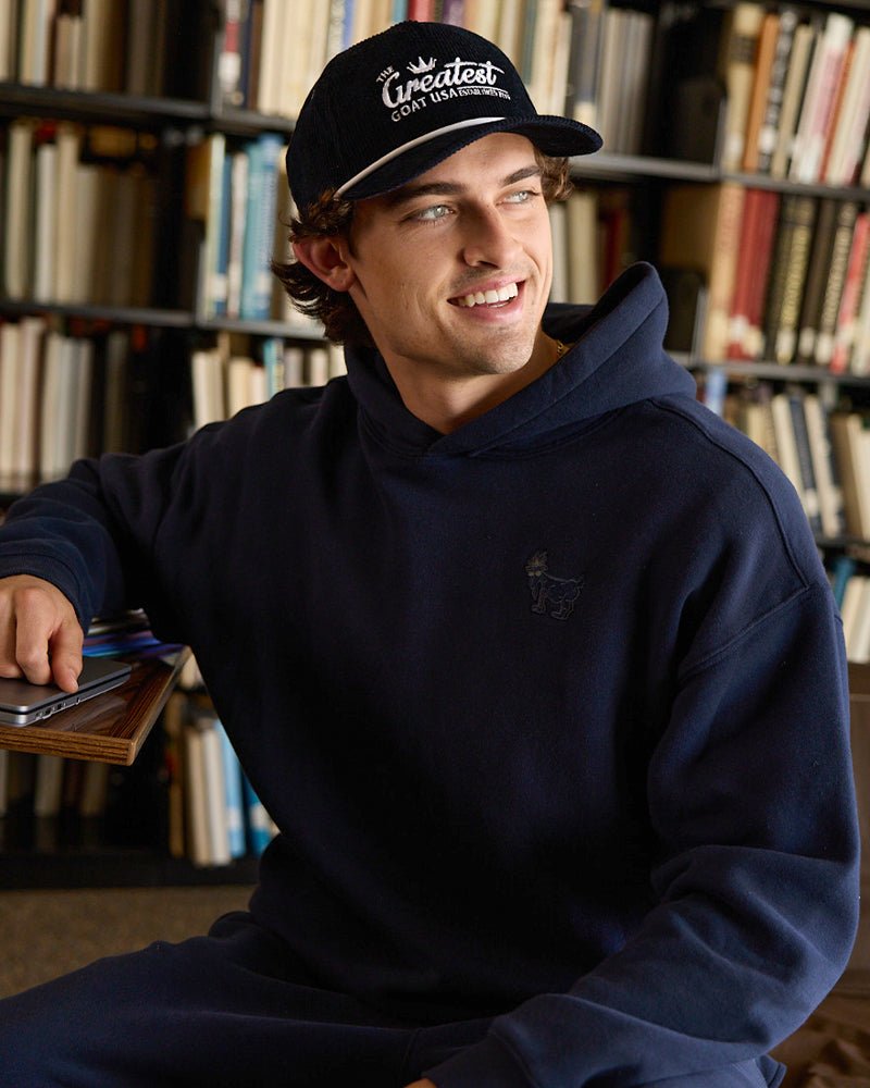 Navy blue hoodie with a small logo on the chest on an adult male model.#color_navy-blazer