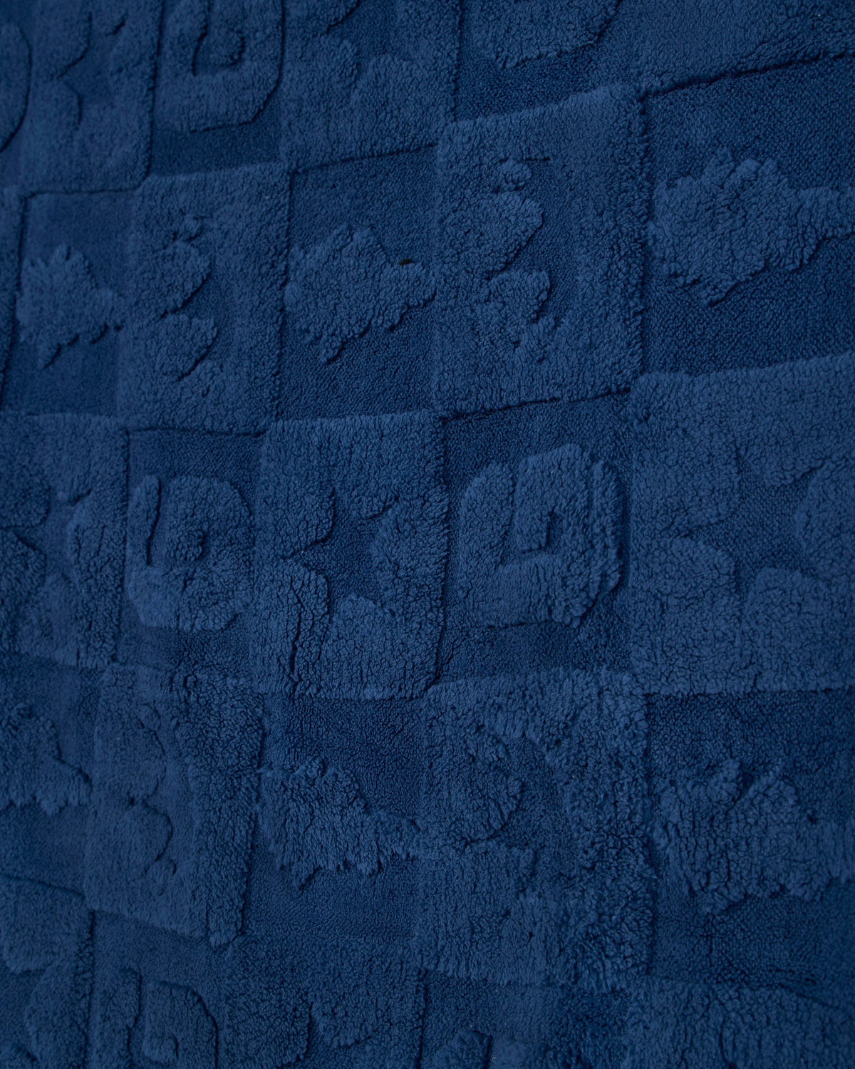 A close-up of a dark navy blue textured fabric with a repeating embossed block pattern.