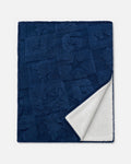 A navy blue textured throw blanket with a white sherpa lining, shown folded to display both sides against a light gray background.