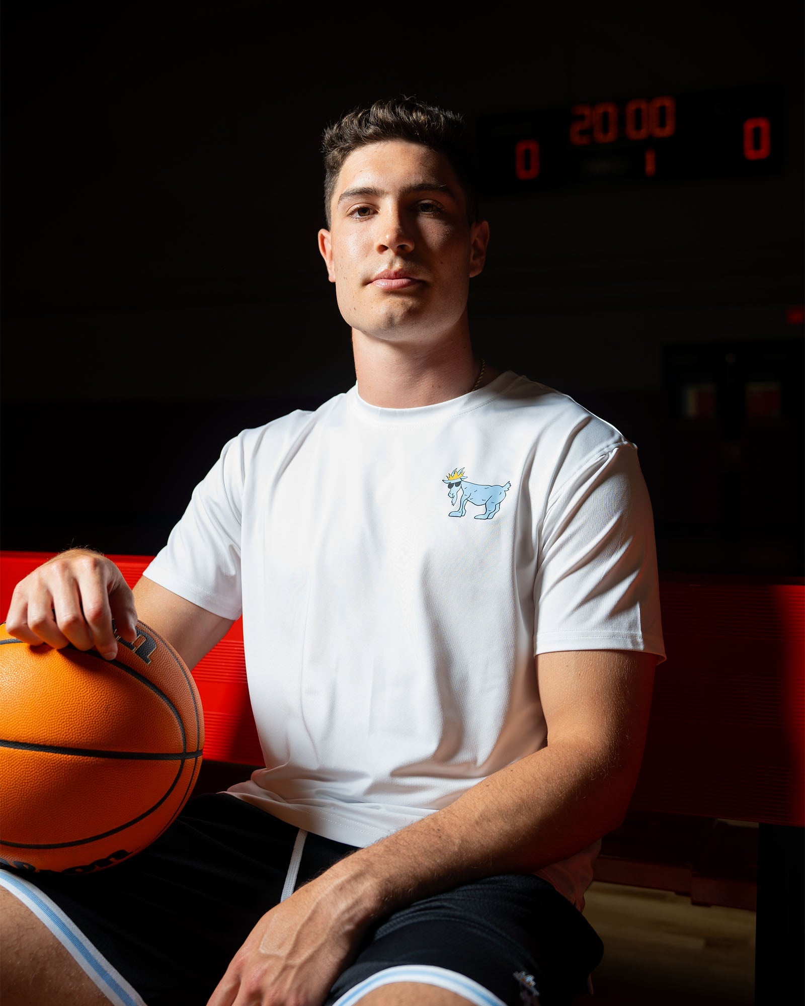 Male basketball player sitting with basketball in lap#color_white