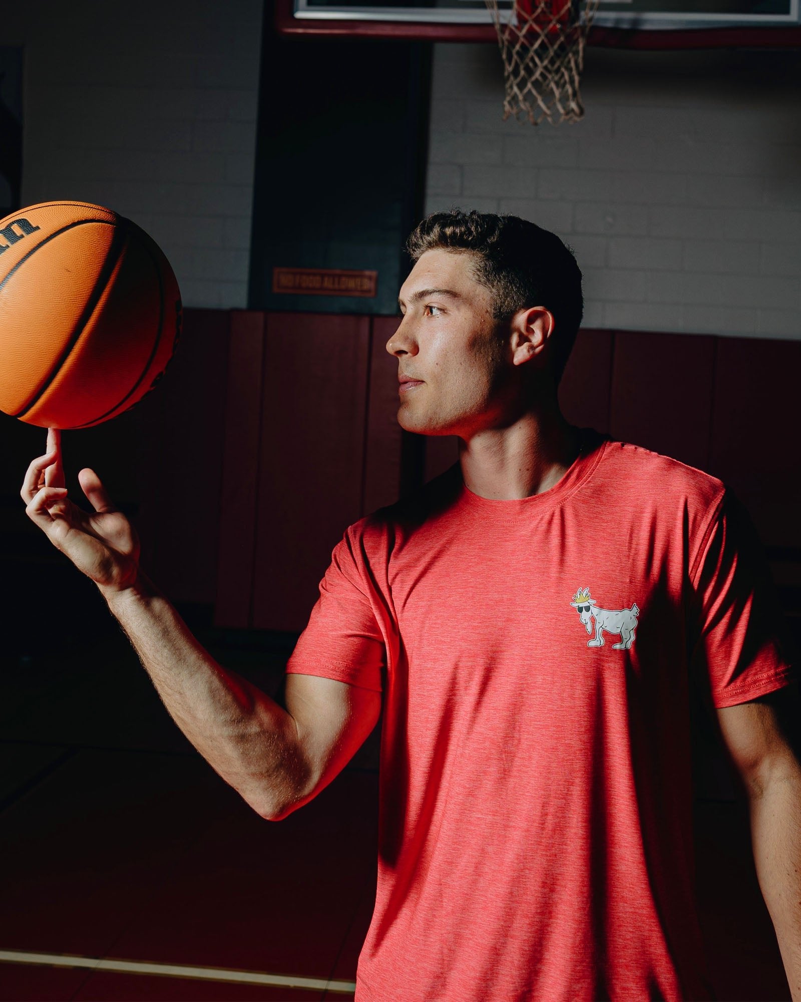 Male spinning a basketball on his finger in a gymnasium#color_red