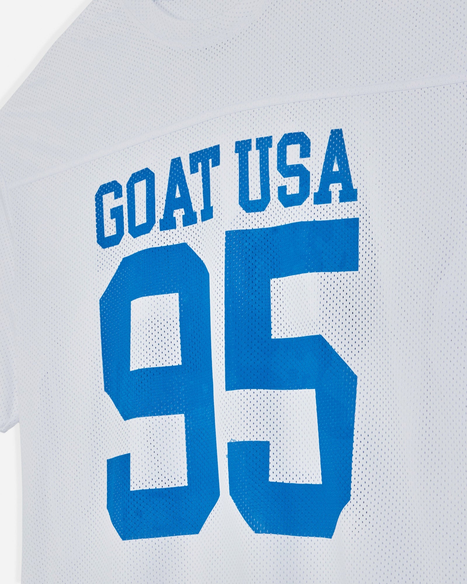 White shirt with blue text 'GOAT USA 95' on a light gray background