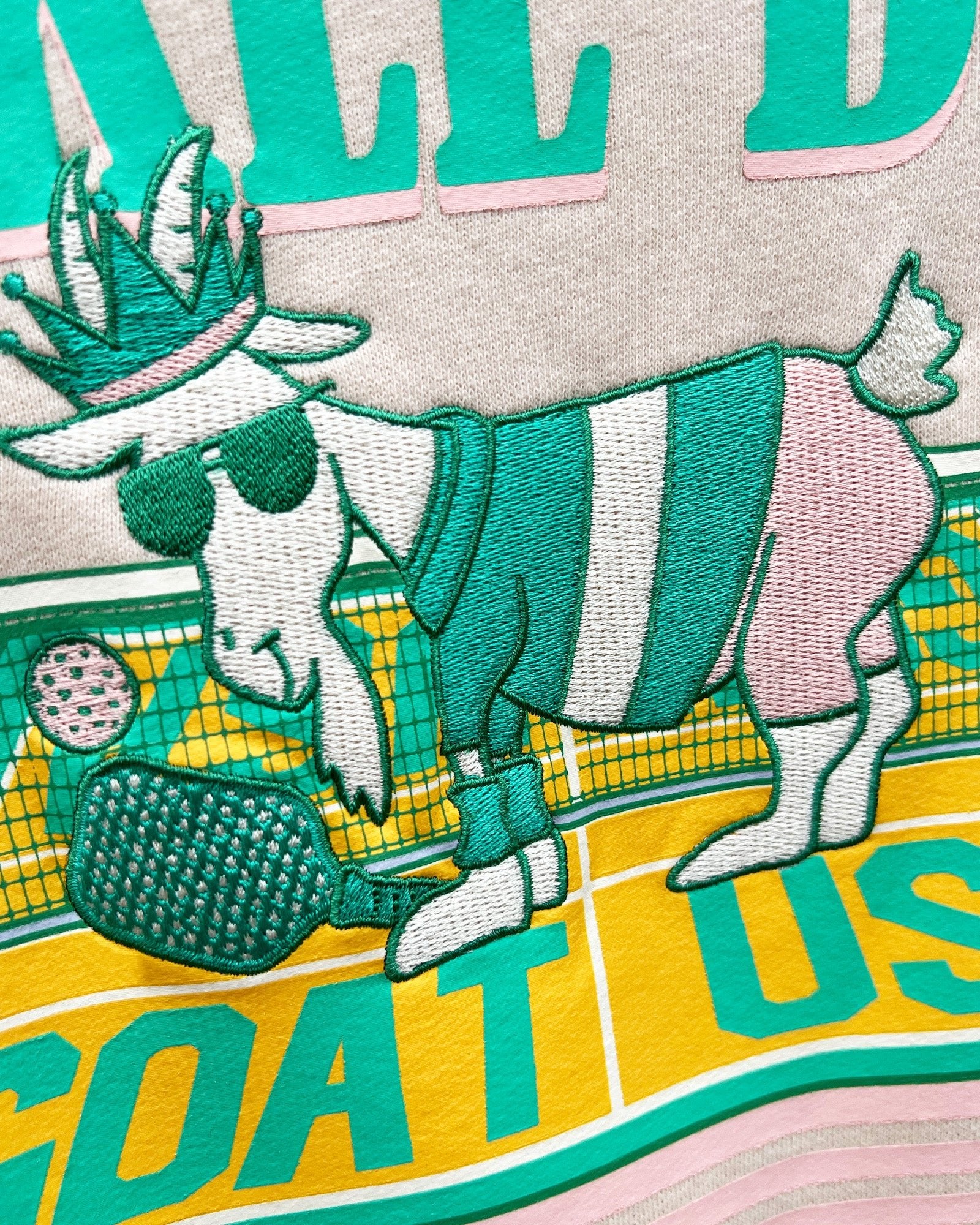 Embroidered patch of a goat wearing a crown and sunglasses with text on a fabric background