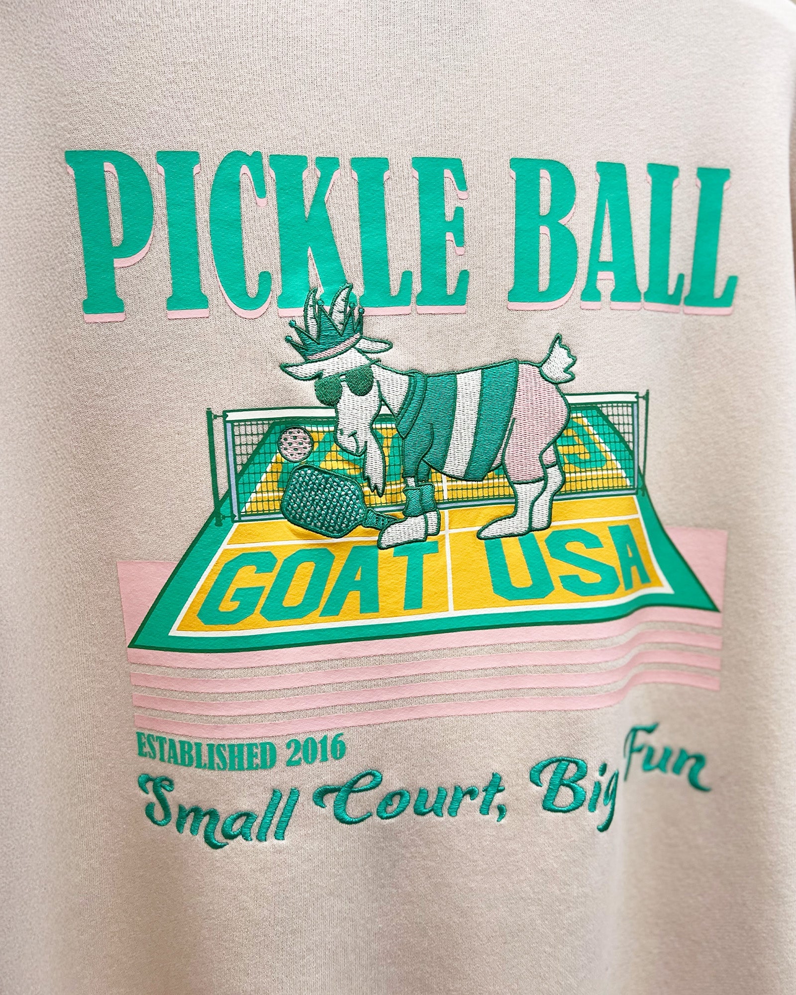 Beige sweatshirt with pickleball-themed design featuring a goat and text.