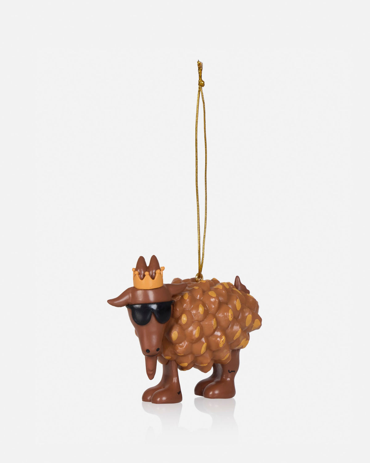 A novelty Christmas ornament shaped like a goat with a textured woolly body, wearing a small gold crown and dark sunglasses, hanging from a thin gold string against a light gray background.