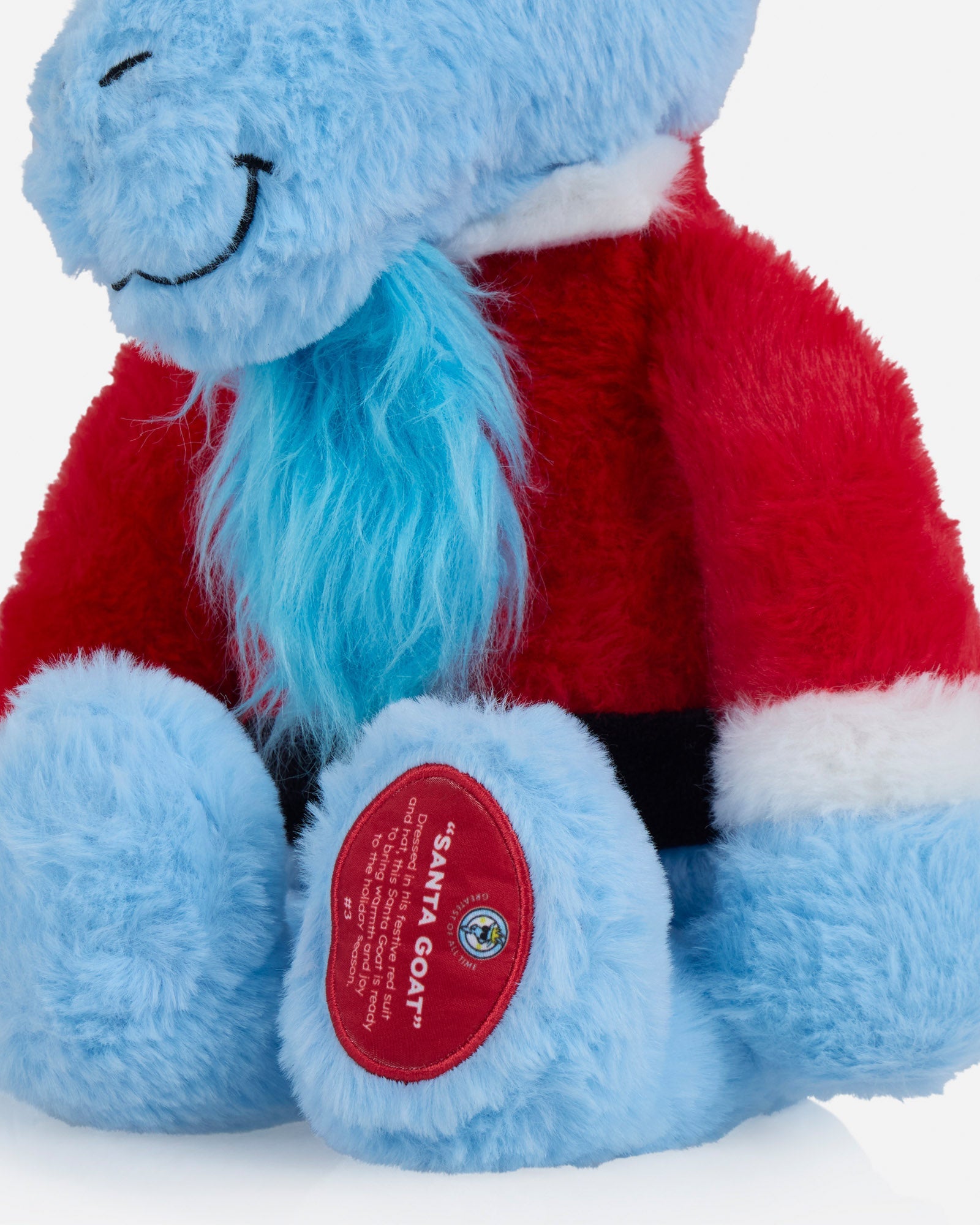 Blue plush toy with a red scarf and a visible brand label on a light gray background